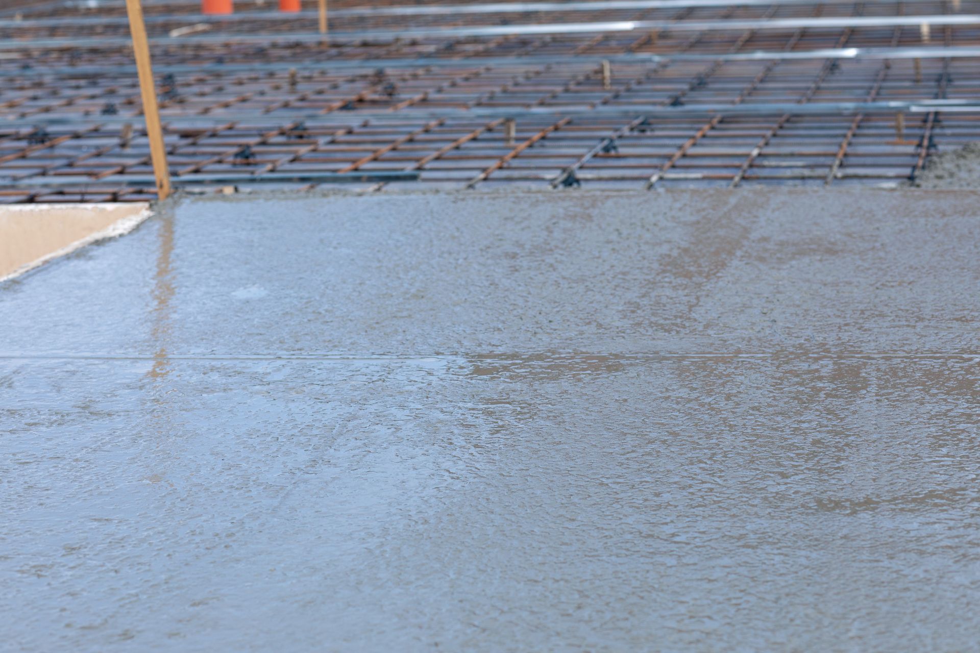 Freshly poured concrete next to rebar on a construction site.