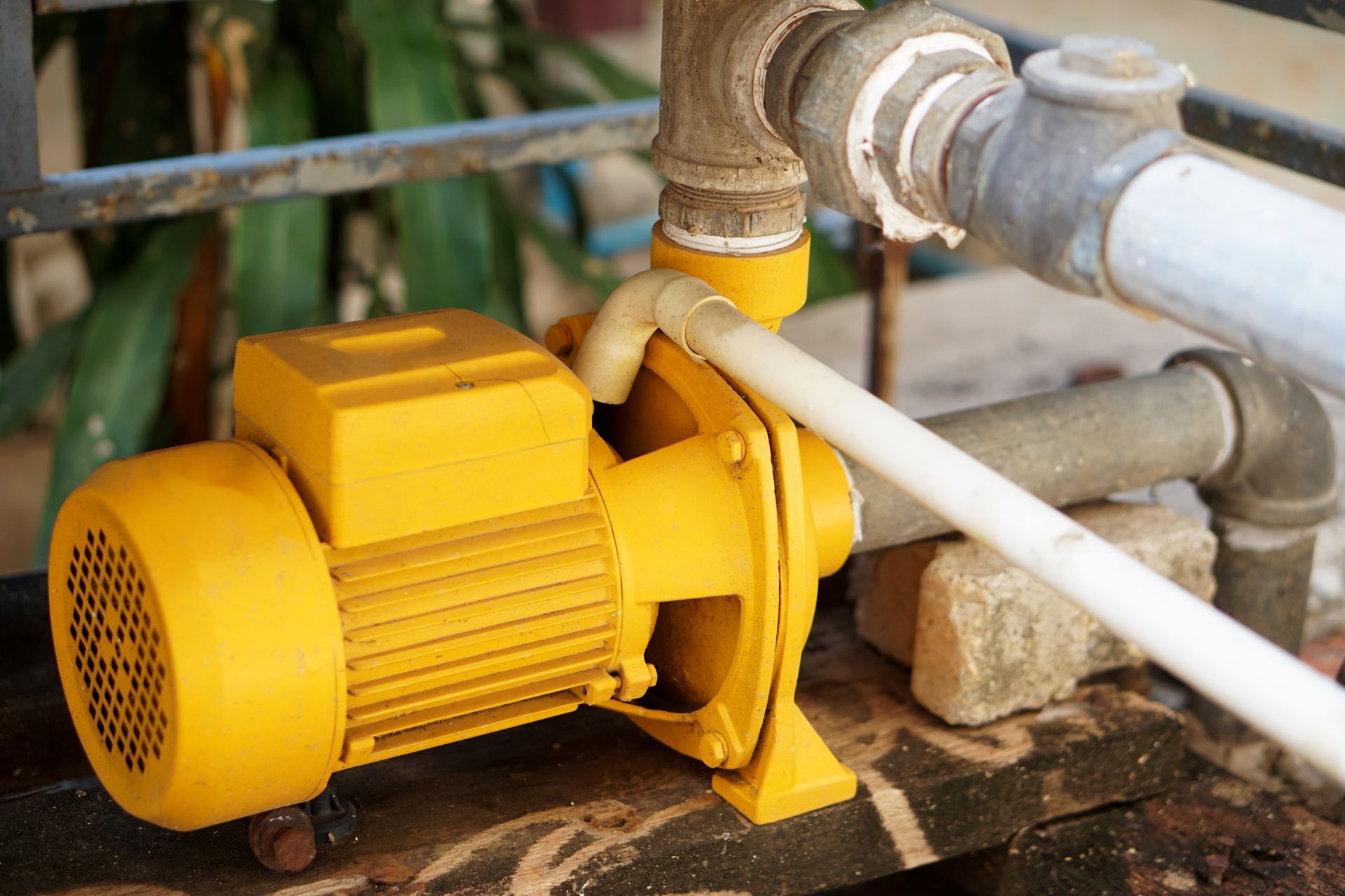 Yellow water pump connected to gray pipes outdoors
