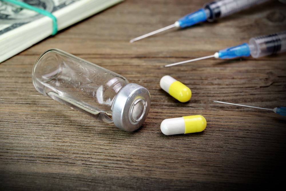 Money, syringes, pills, and an empty vial on a wooden surface, suggesting drug use.