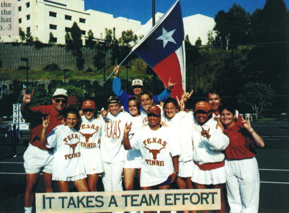 A group wearing Texas Tennis shirts and holding a Texas flag poses outdoors above a sign reading 