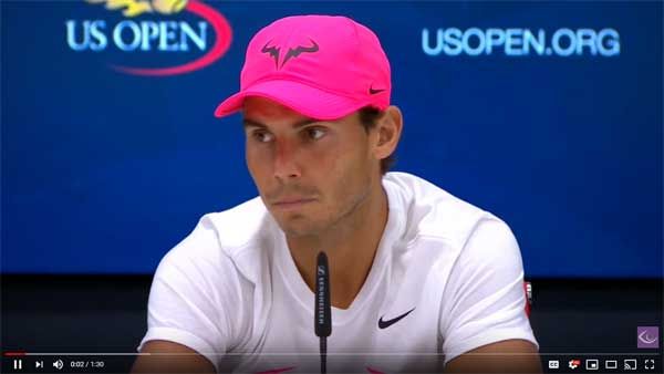 A man wearing a pink hat is sitting in front of a us open sign