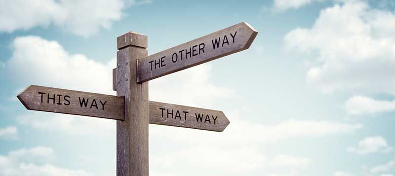 A wooden signpost with three arrows pointing in different directions.