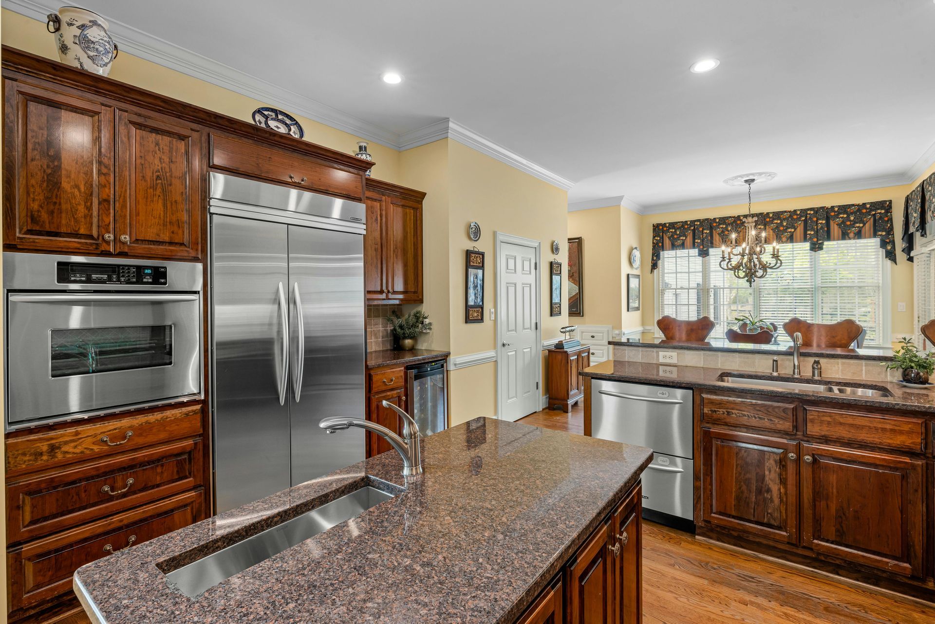 Modern kitchen with stainless steel appliances, dark wood cabinets, granite island, and breakfast nook