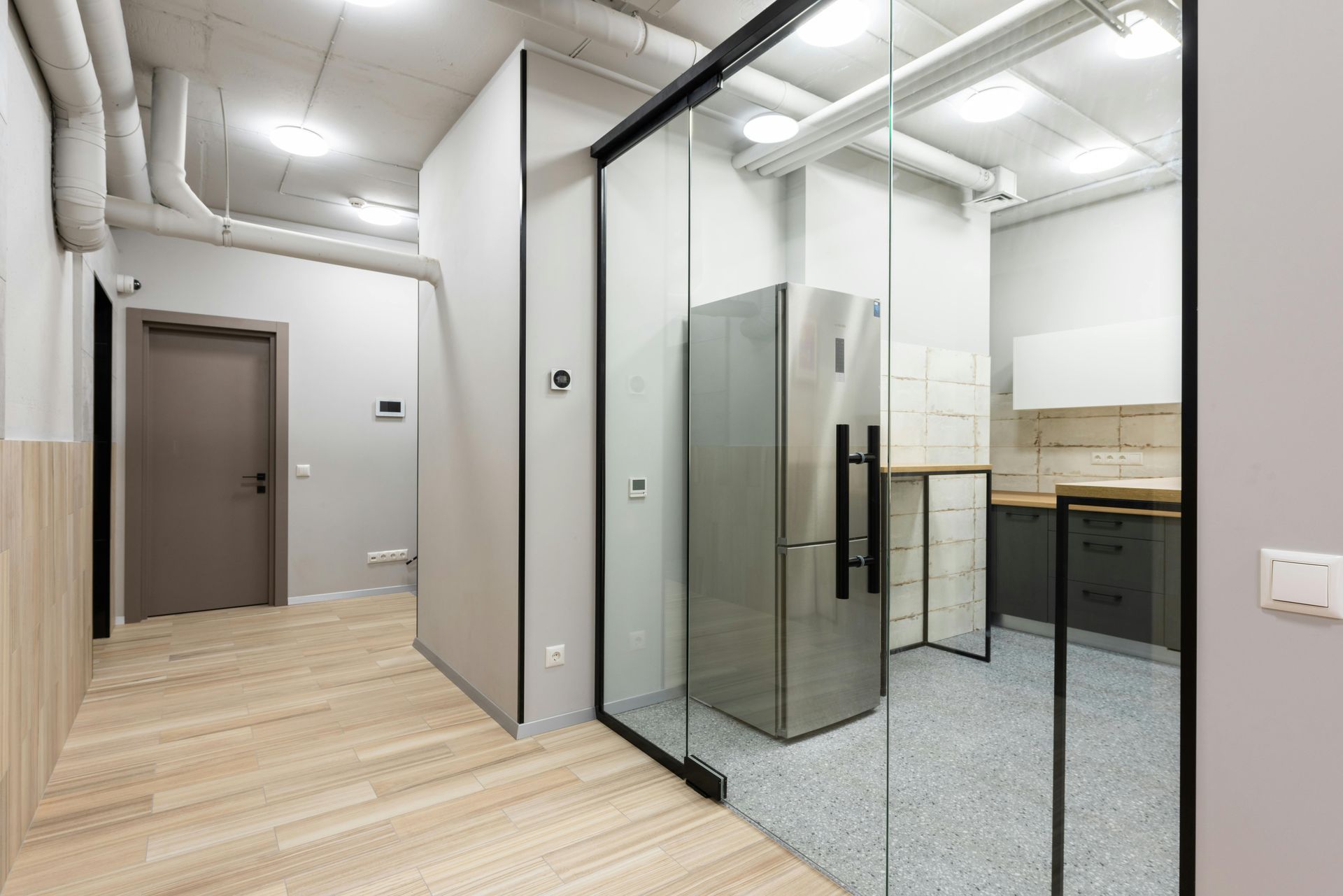 Modern office hallway with glass-walled meeting room and wood floors