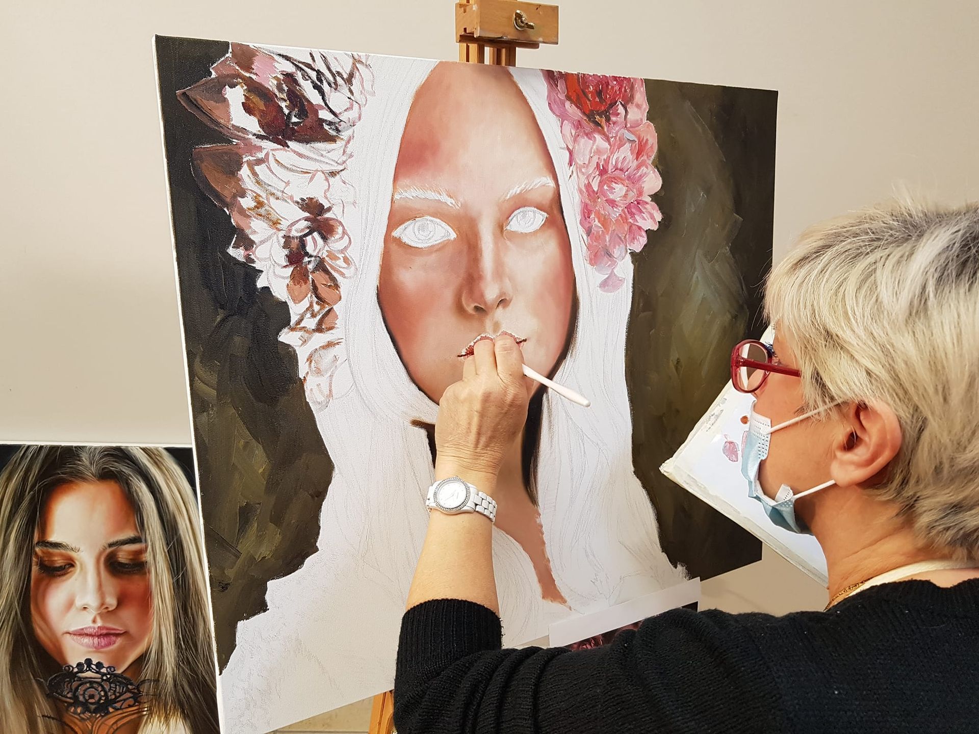 Una donna sta dipingendo un volto femminile su un cavalletto.