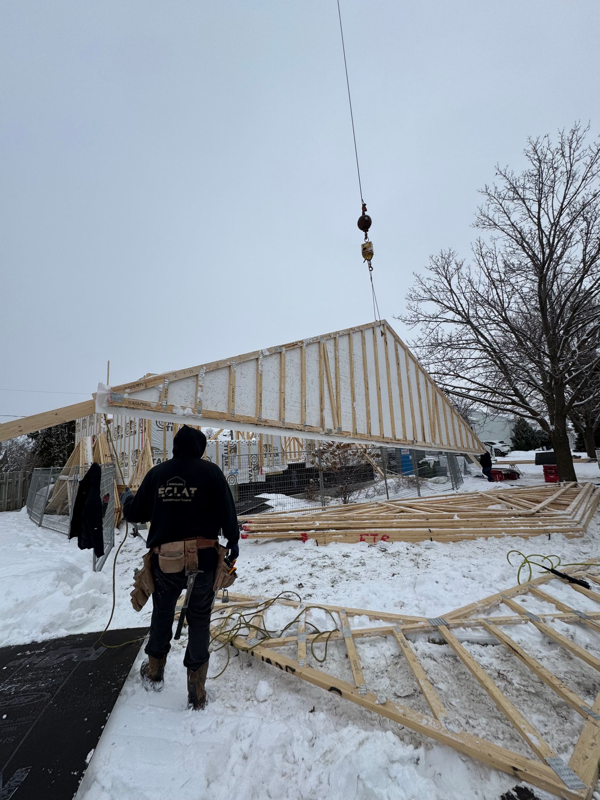 Un homme marche dans la neige devant un immeuble en construction.