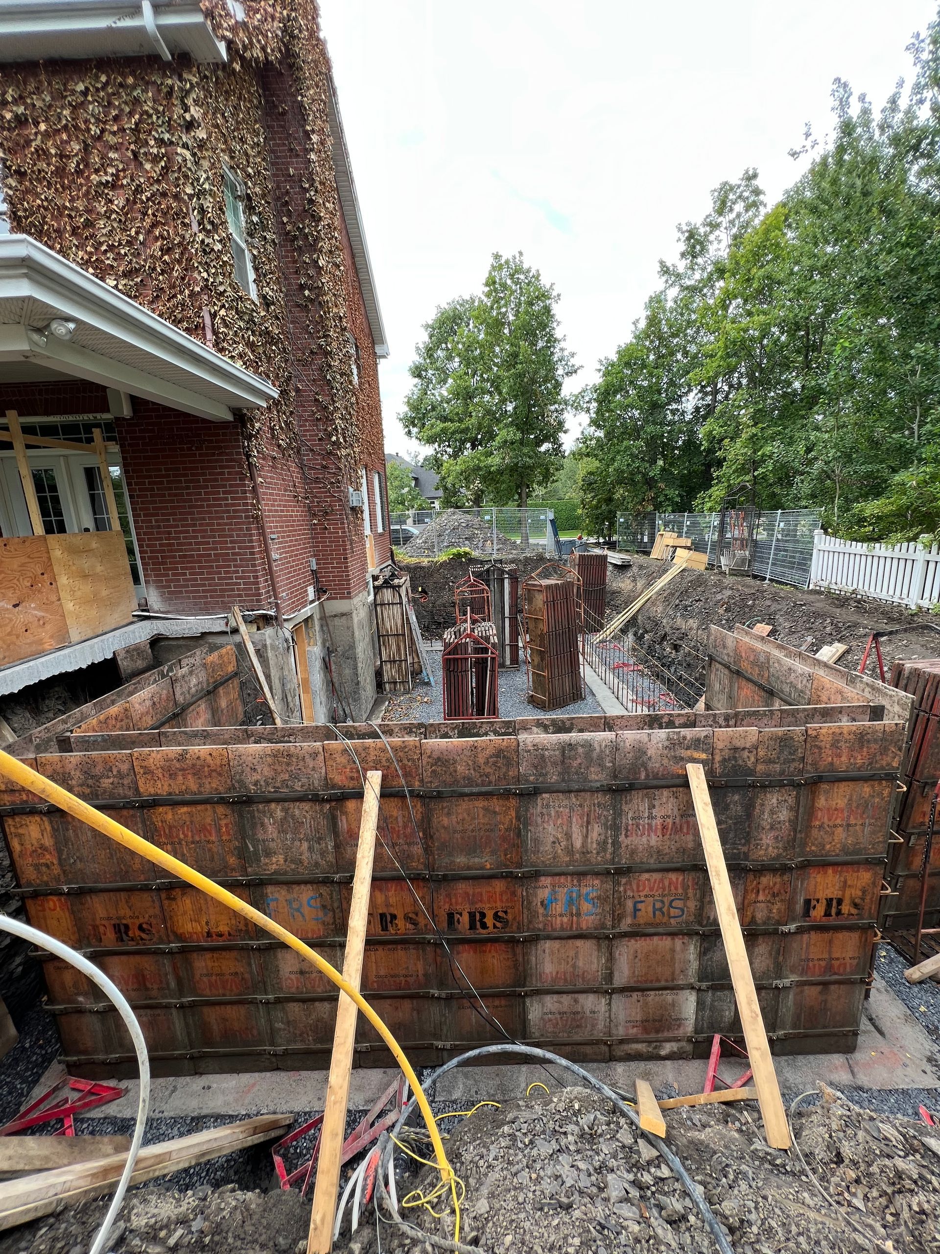 Un grand mur de béton est en cours de construction devant un bâtiment en briques.
