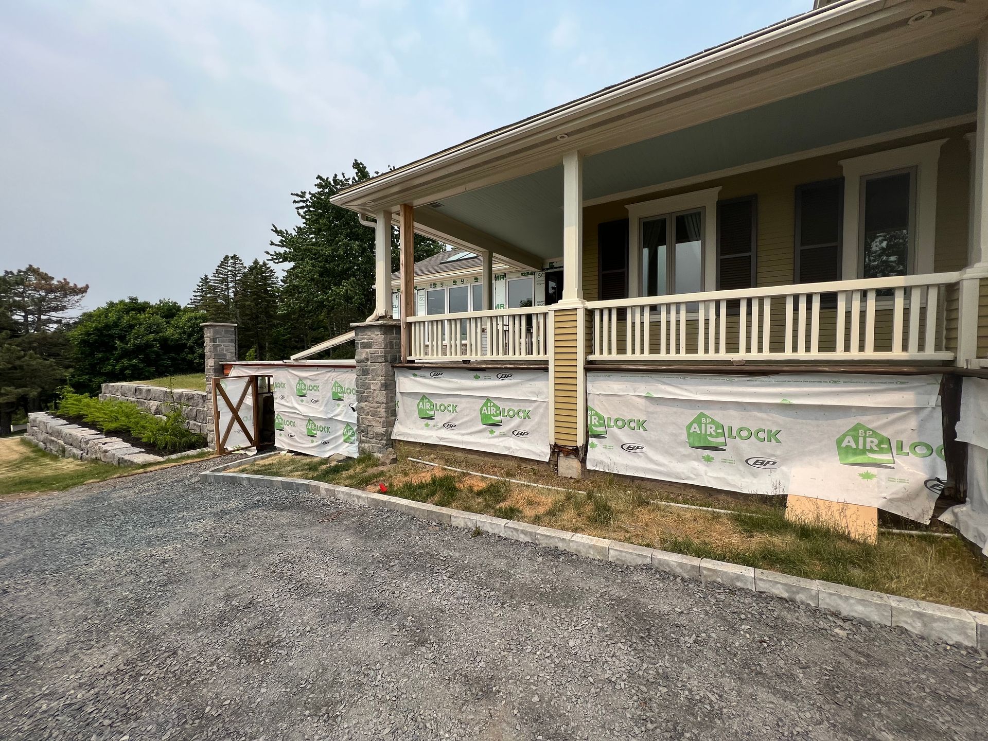 Une maison est en construction avec un grand porche et une allée en gravier.