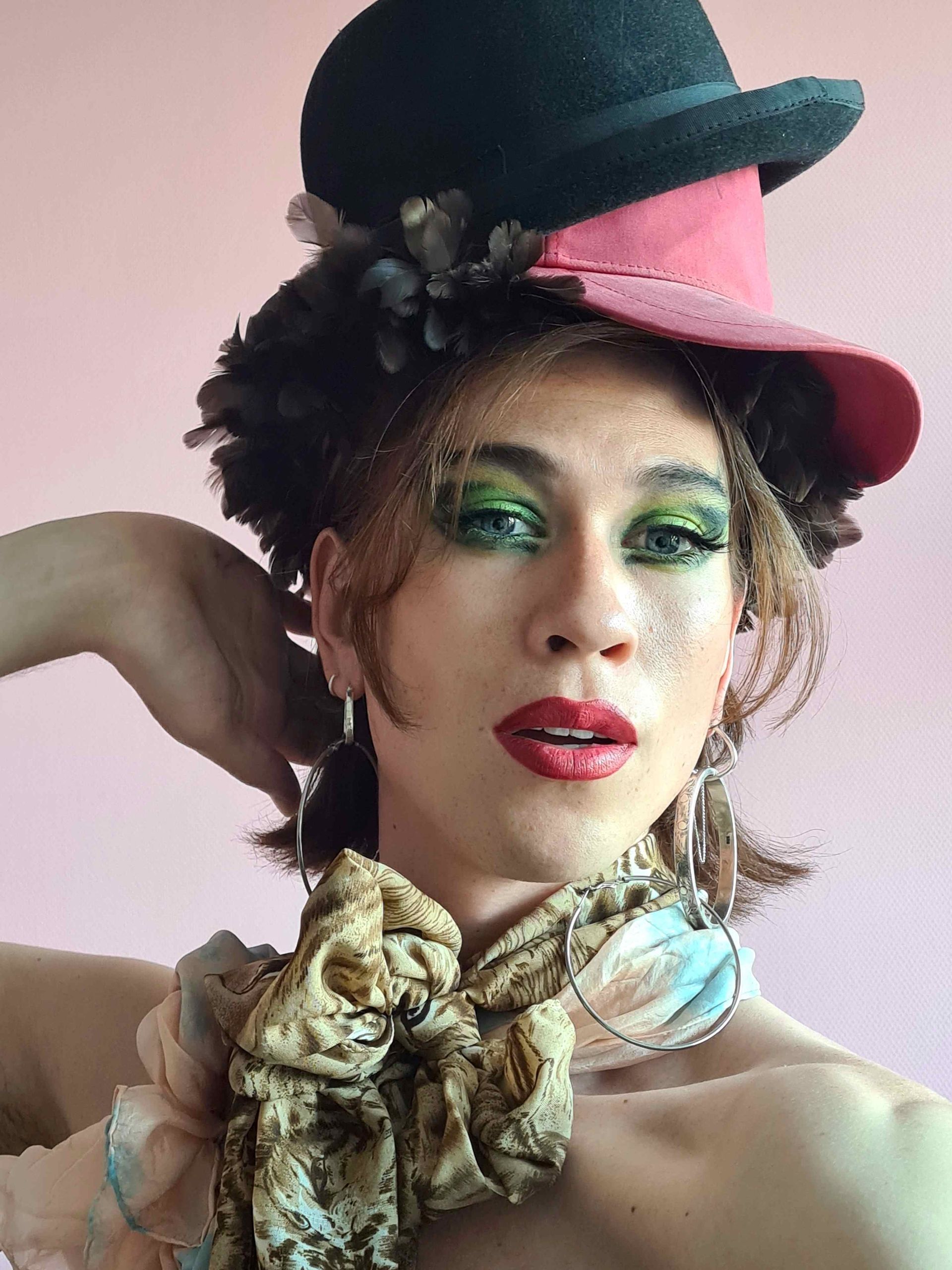 Barry de Bruin draagt ​​een geruit overhemd en een ketting en staat voor een blauwe achtergrond. Barry staat bij Nederlied in de voorstelling Pride Show Zingend uit de kast, in theater Het Zonnehuis in Amsterdam.