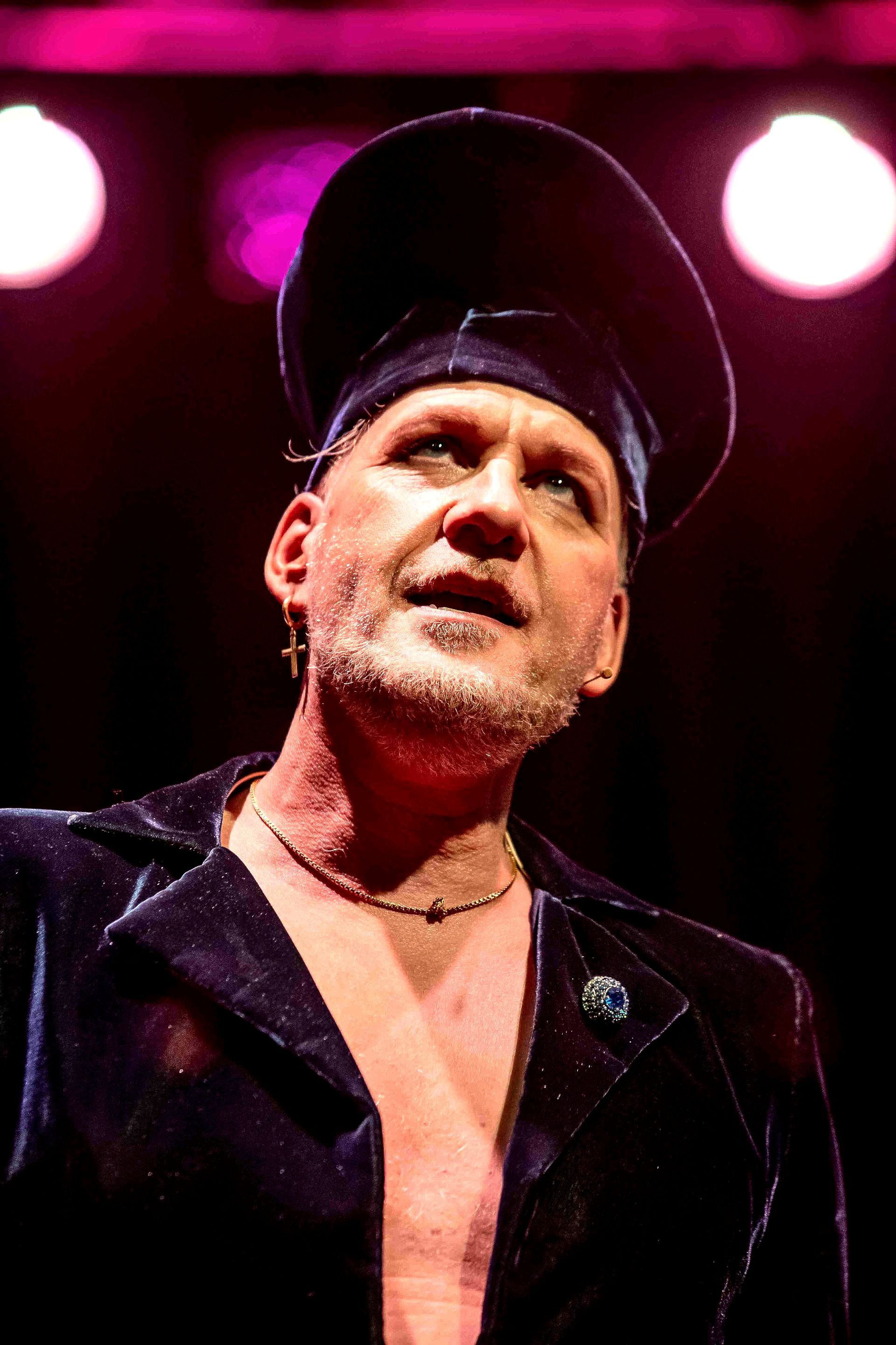 Bart Steenbeek Alexei. Een foto van een man met een hoed en een jas staat op een podium. Nederlied Theater het Zonnehuis Amsterdam