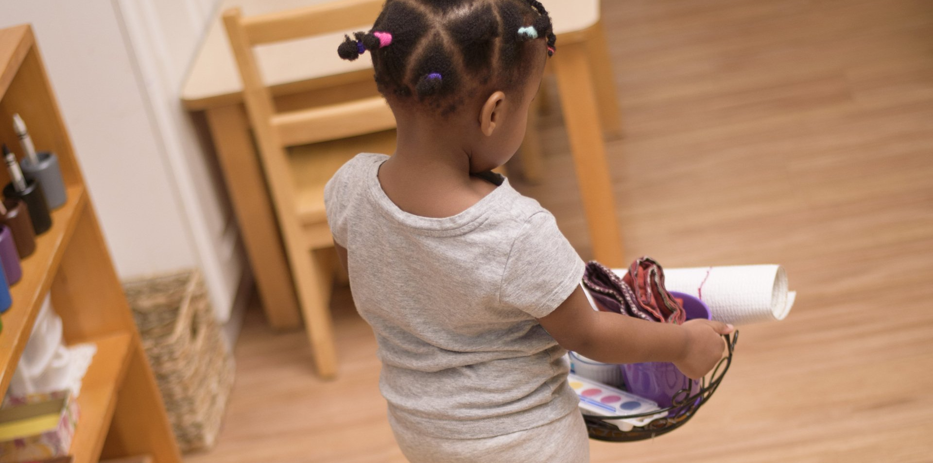 Child carrying Montessori materials