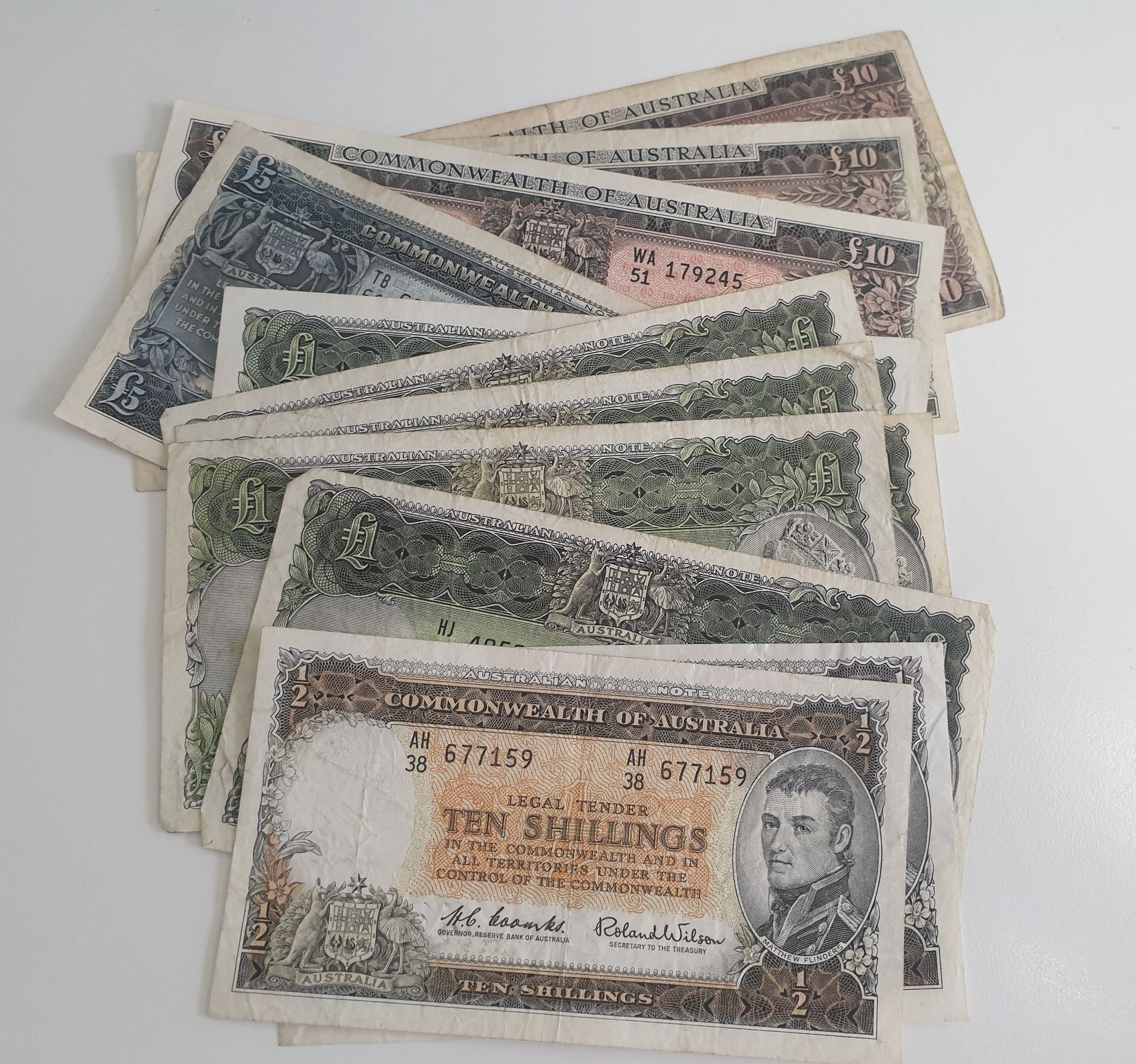 Stack of pre-decimal Australian banknotes including Ten Shillings, One Pound, and higher denominations, used in currency auctions and collecting.