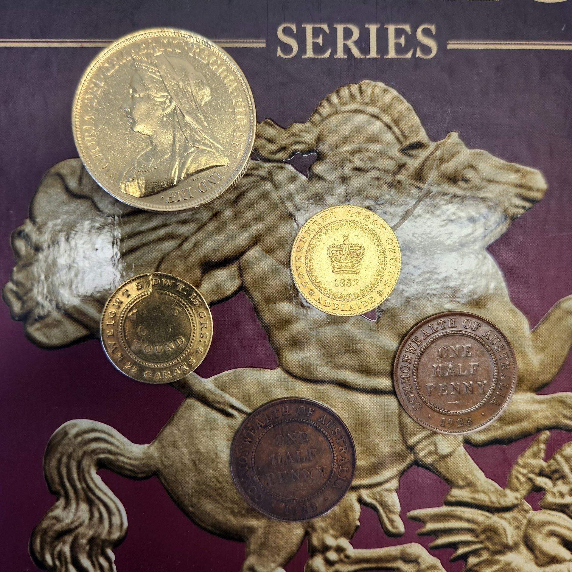 Collection of rare Australian coins including the 1852 Adelaide Pound, Queen Victoria sovereign, and pre-decimal halfpennies on a numismatic display card.