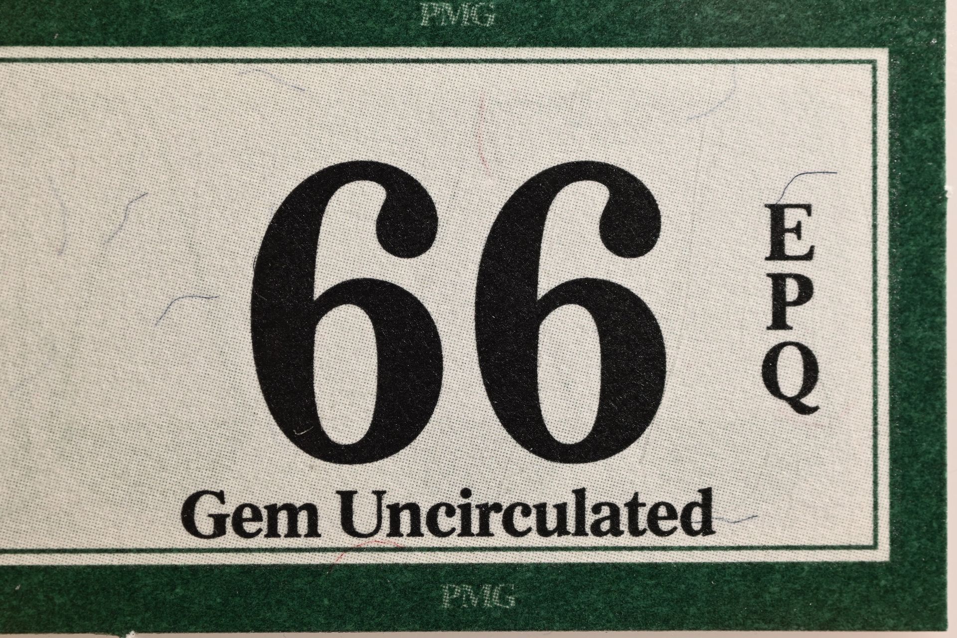Close-up of the 66 EPQ Gem Uncirculated grade on the counterfeit PMG label, showing different text alignment and positioning