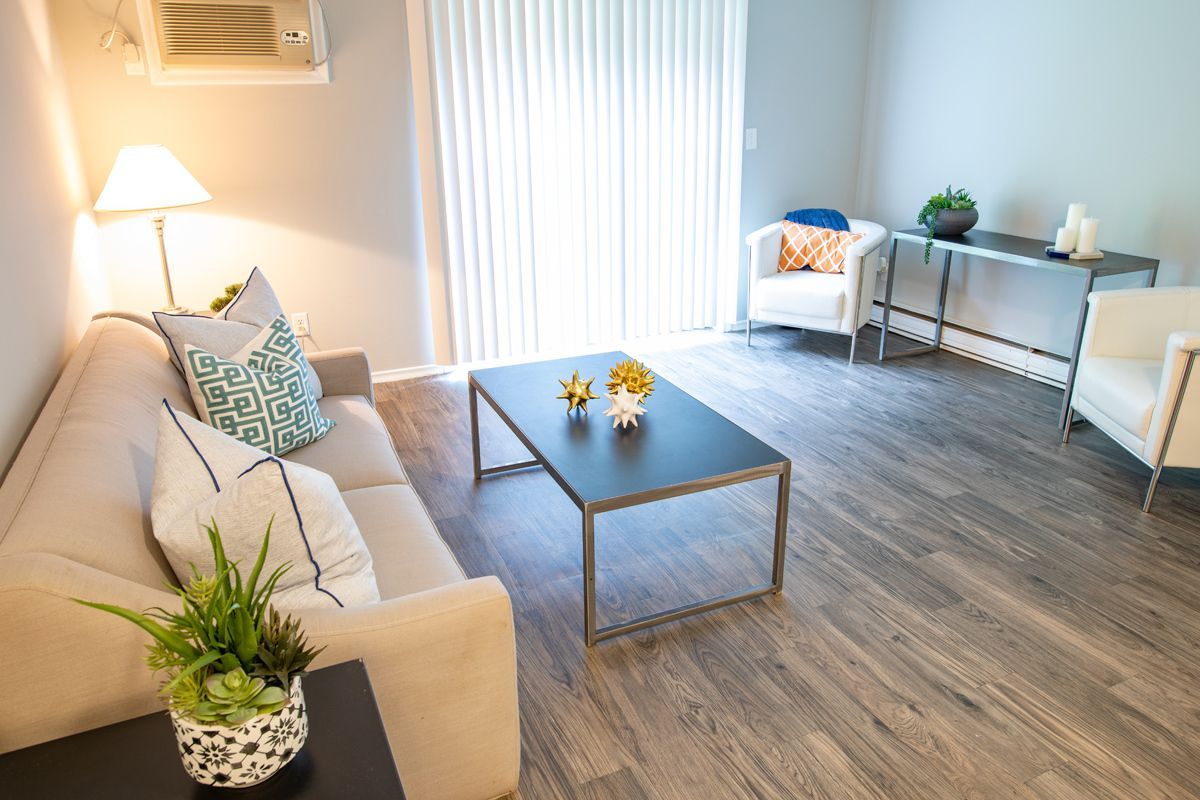Living room with beige couch, coffee table, white chairs, and sliding glass door.