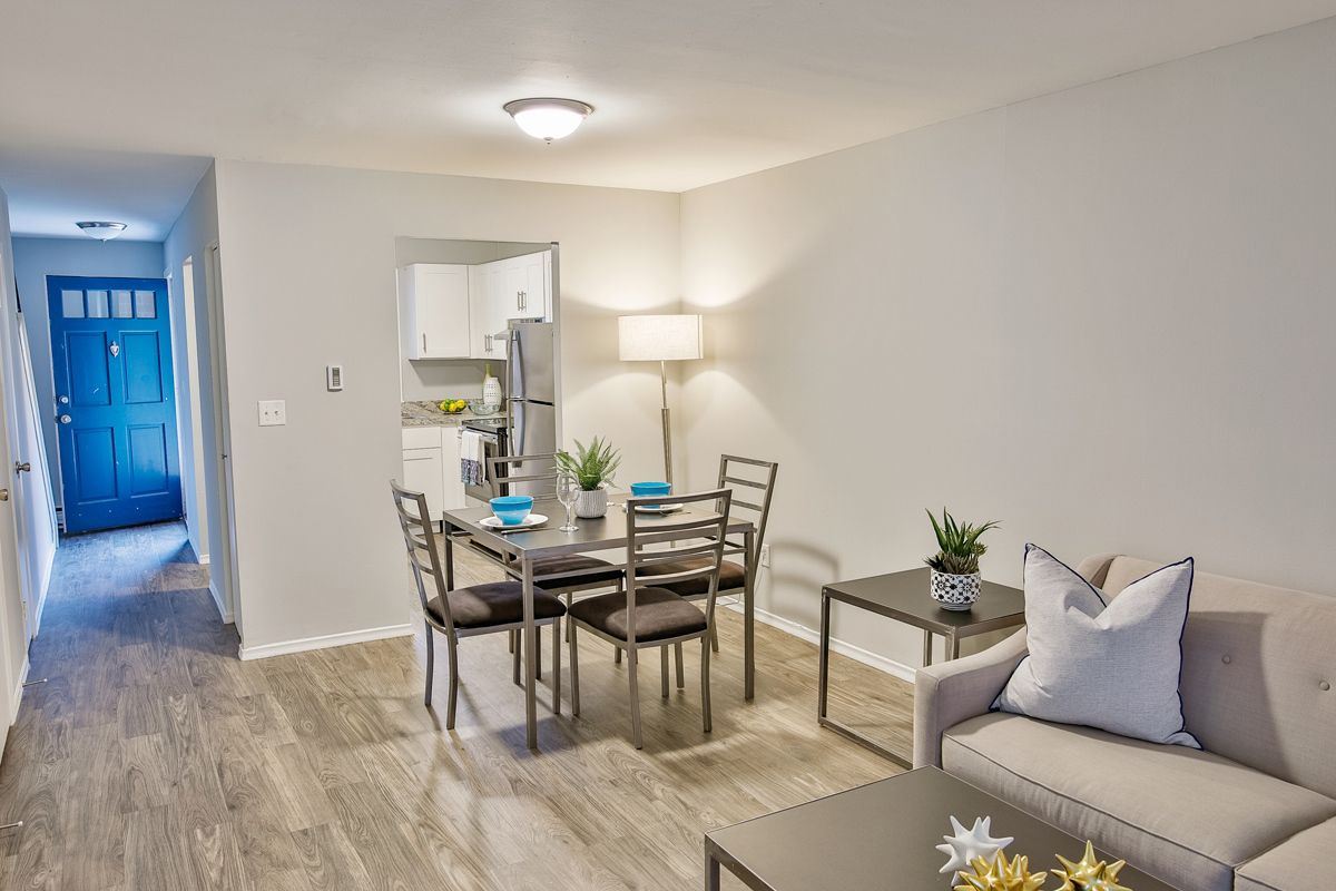 Living room with dining set, sofa, and a doorway leading to the kitchen and front door.