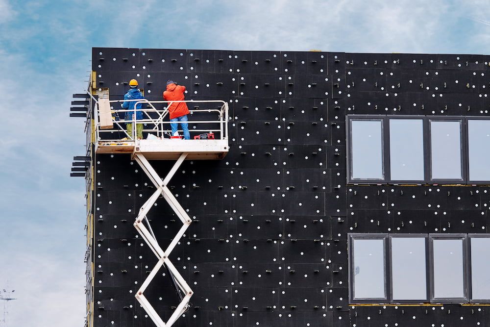 Two Construction Workers Are Working on the Side of a Building — MPE Adventure Quads & Bikes In Wyong, NSW