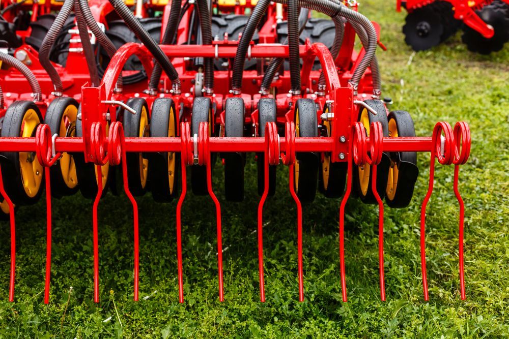 A Red and Yellow Tractor is Sitting on Top of a Lush Green Field — MPE Adventure Quads & Bikes In Cessnock, NSW