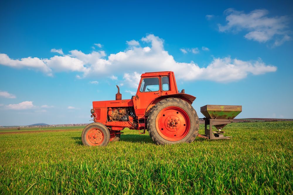 An Old Red Tractor is Sitting in a Grassy Field — MPE Adventure Quads & Bikes In Newcastle, NSW