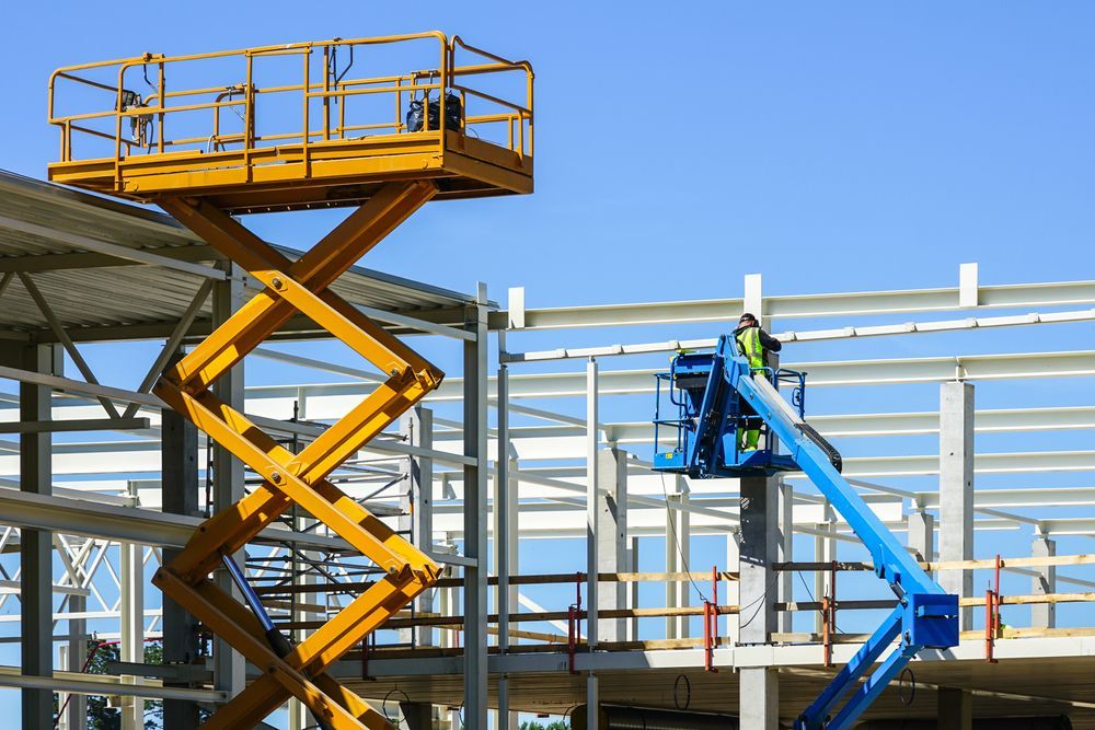 A Man is Working on a Scissor Lift at a Construction Site — MPE Adventure Quads & Bikes In Gosford, NSW