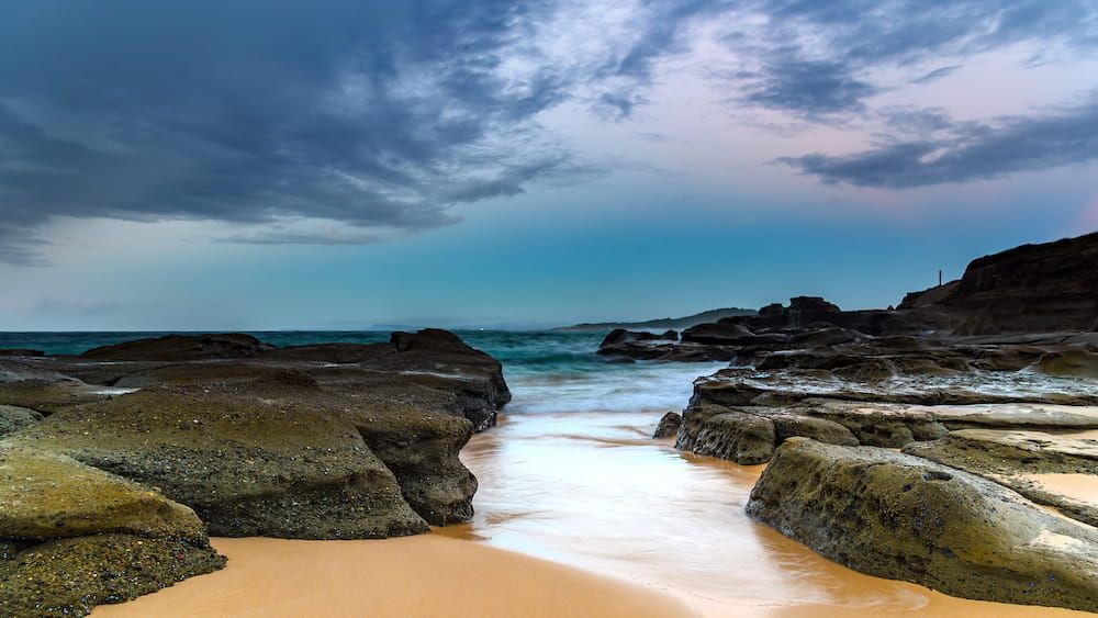 A Beach With Rocks and Waves Coming in on a Cloudy Day — MPE Adventure Quads & Bikes In Wyong, NSW