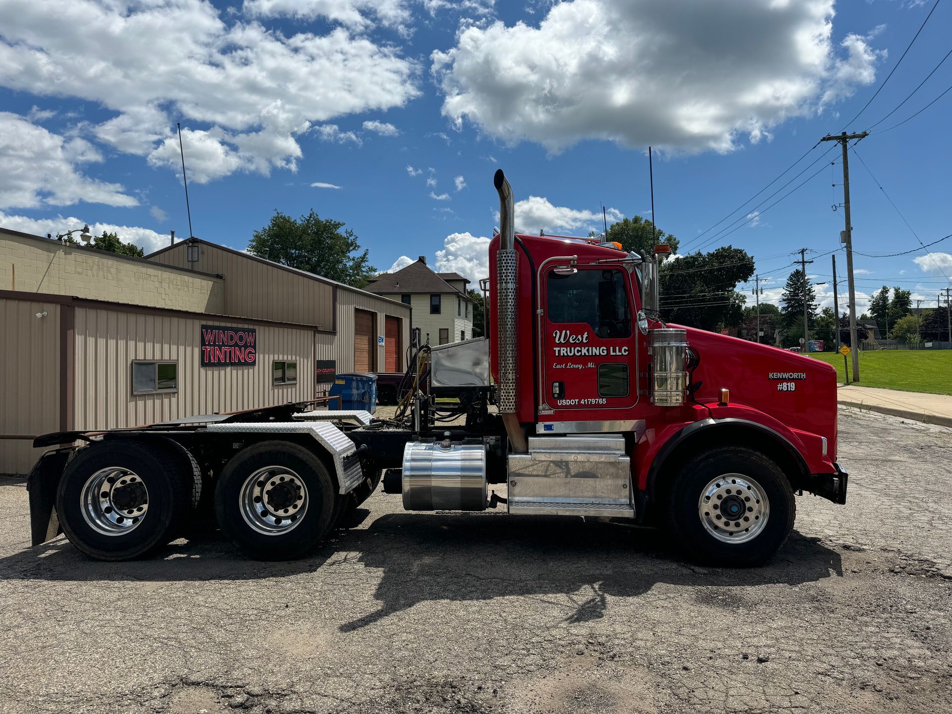 A red semi truck is parked in front of a building.