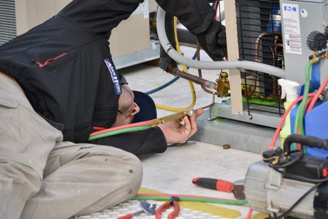 HVAC repair technician welding copper lines on outdoor unit for Alex HVAC Service LLC
