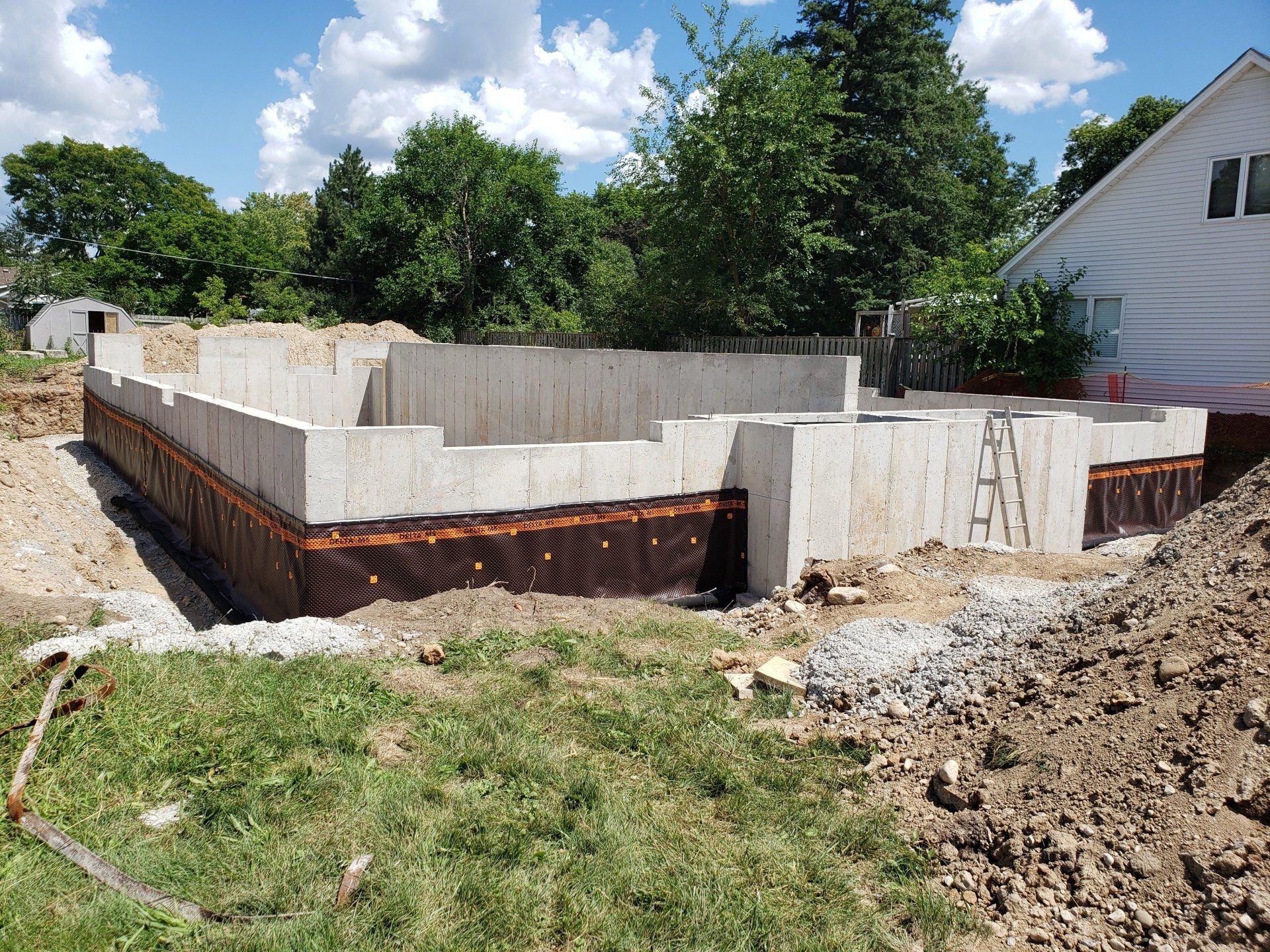 A concrete foundation is being built in the backyard of a house