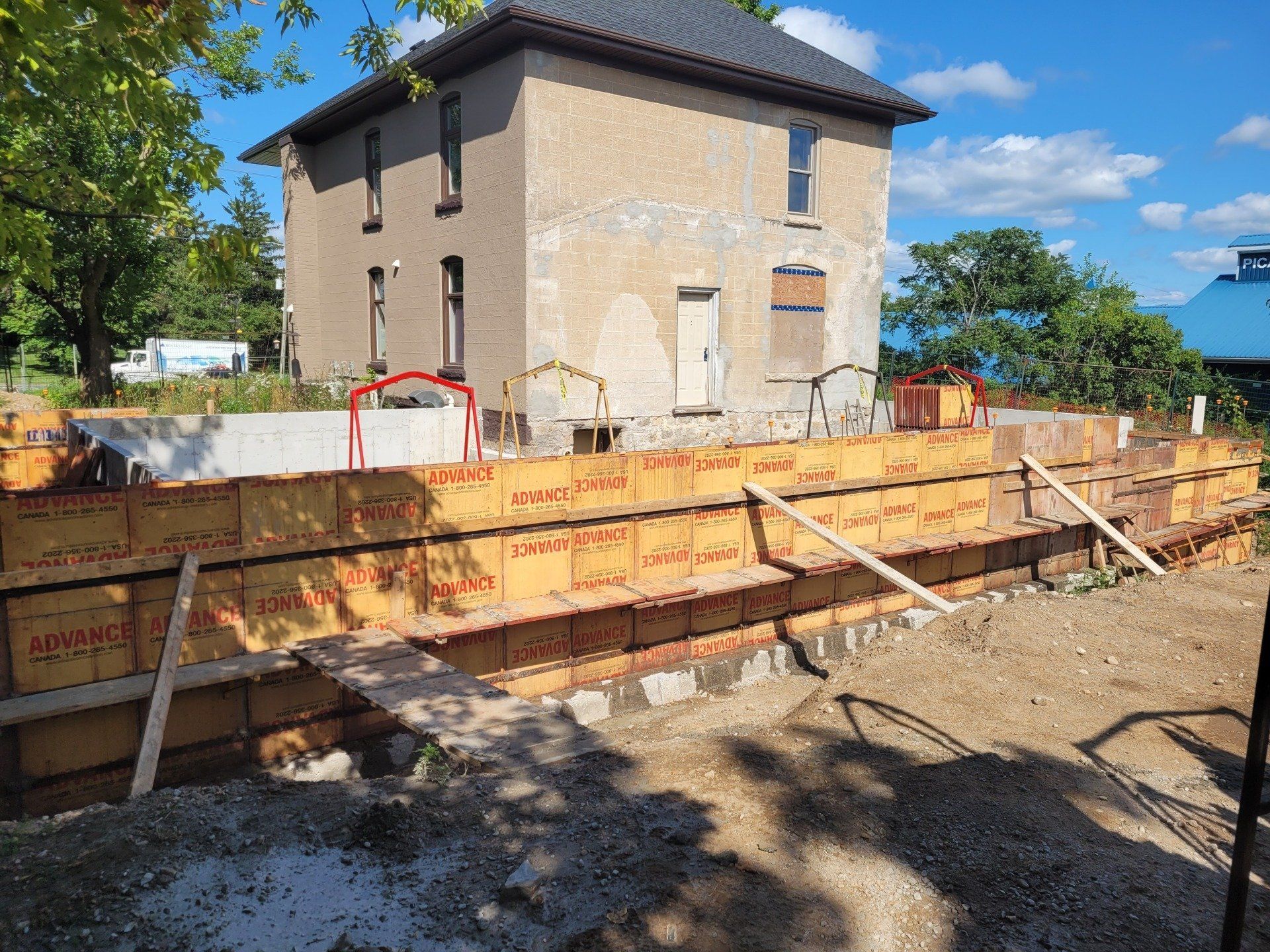 A large house is being built in the middle of a dirt field.