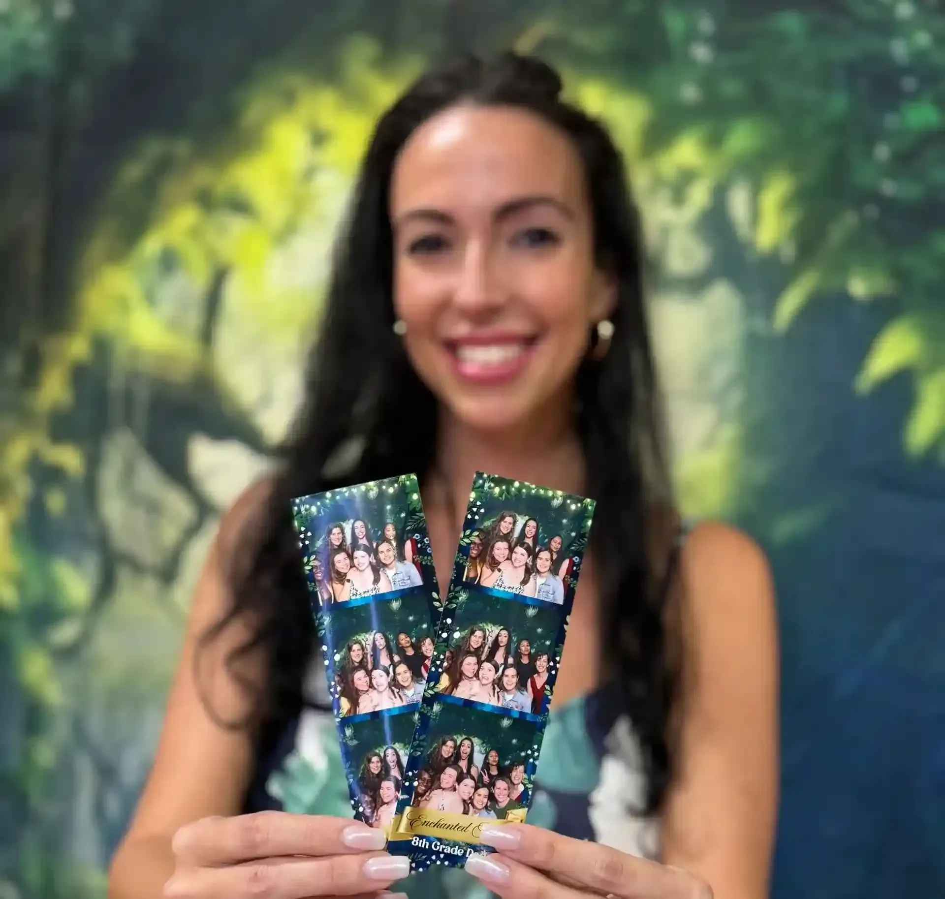 A smiling guest holding photo booth 2x6 strips
