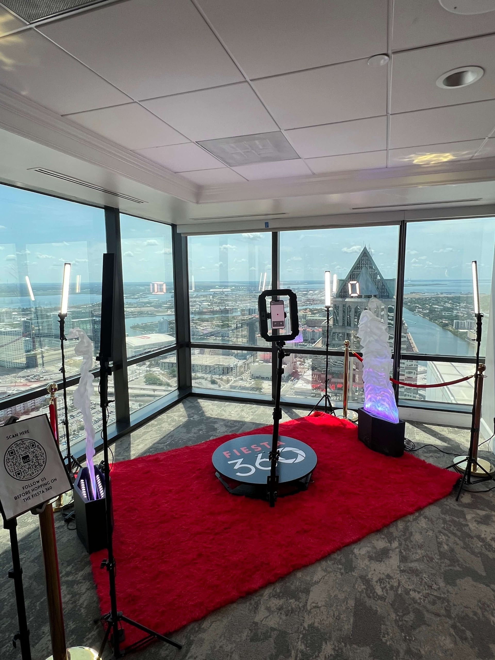 A room with a red rug and a 360 degree photo booth.