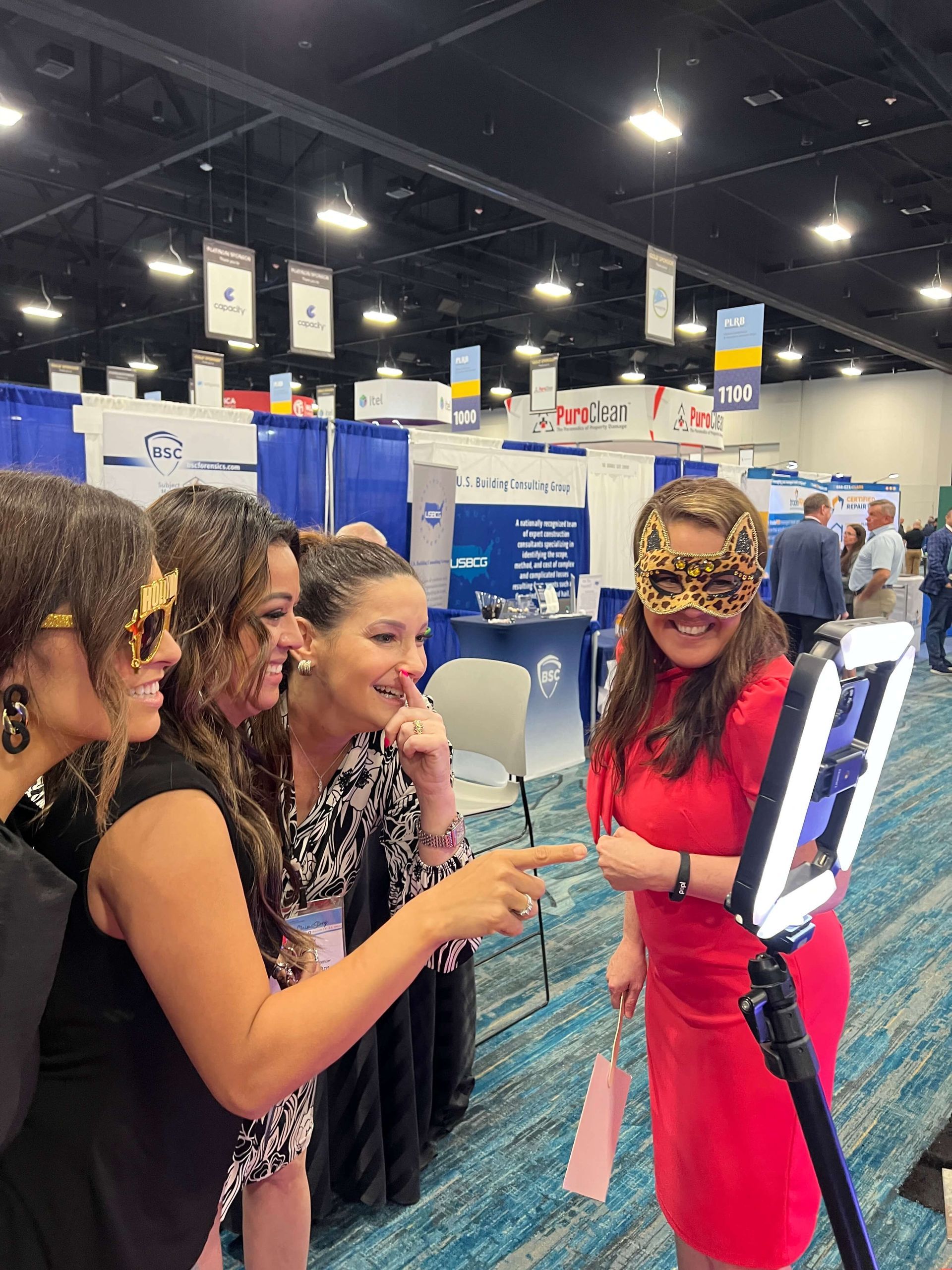 A group of women are standing around a woman wearing a mask.
