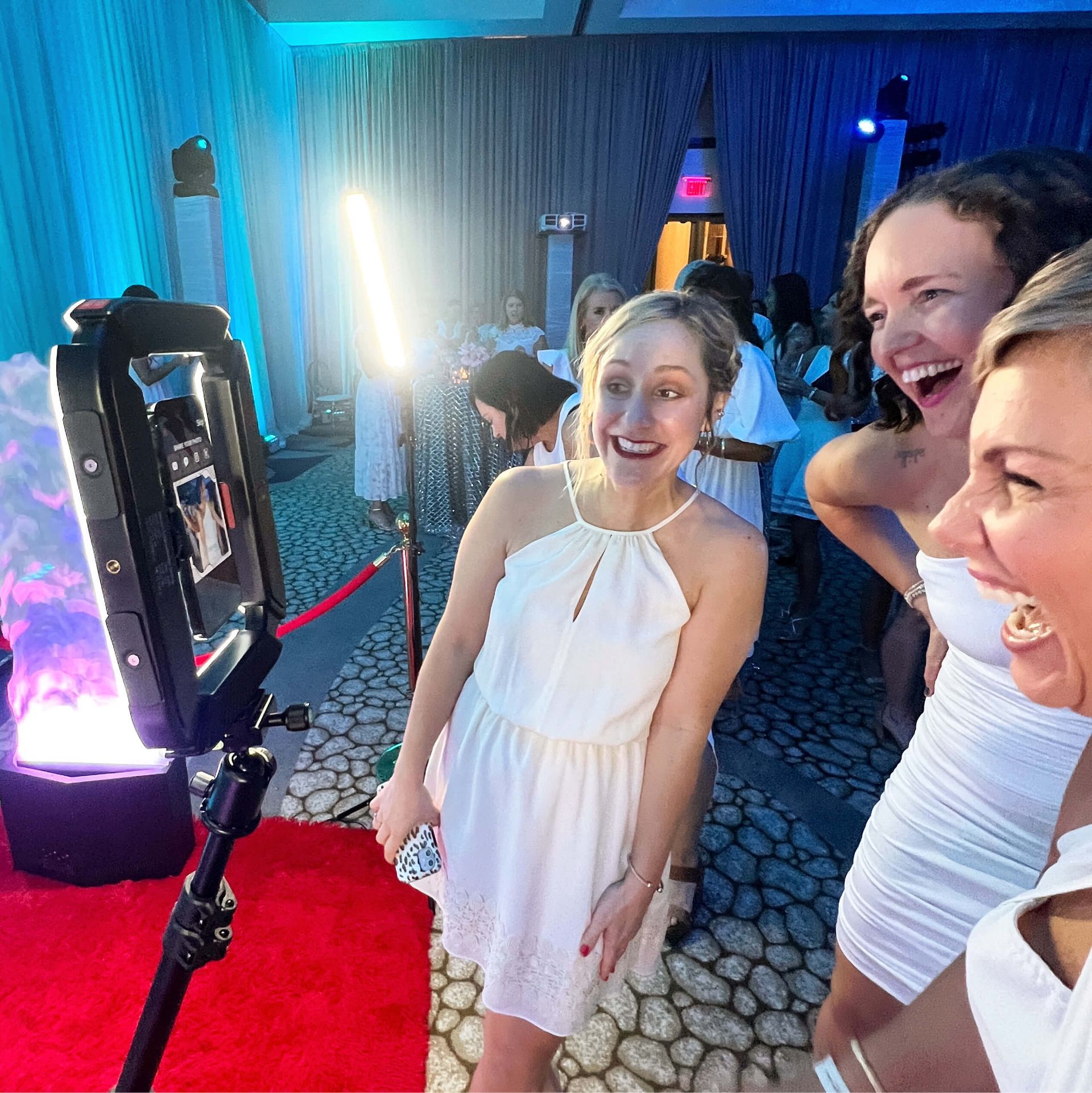 A group of women are standing in front of a photo booth.