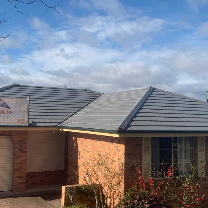 A Brick House With A Gray Tiles Roof — Lance Ward Roof Tiling in Orange, NSW 