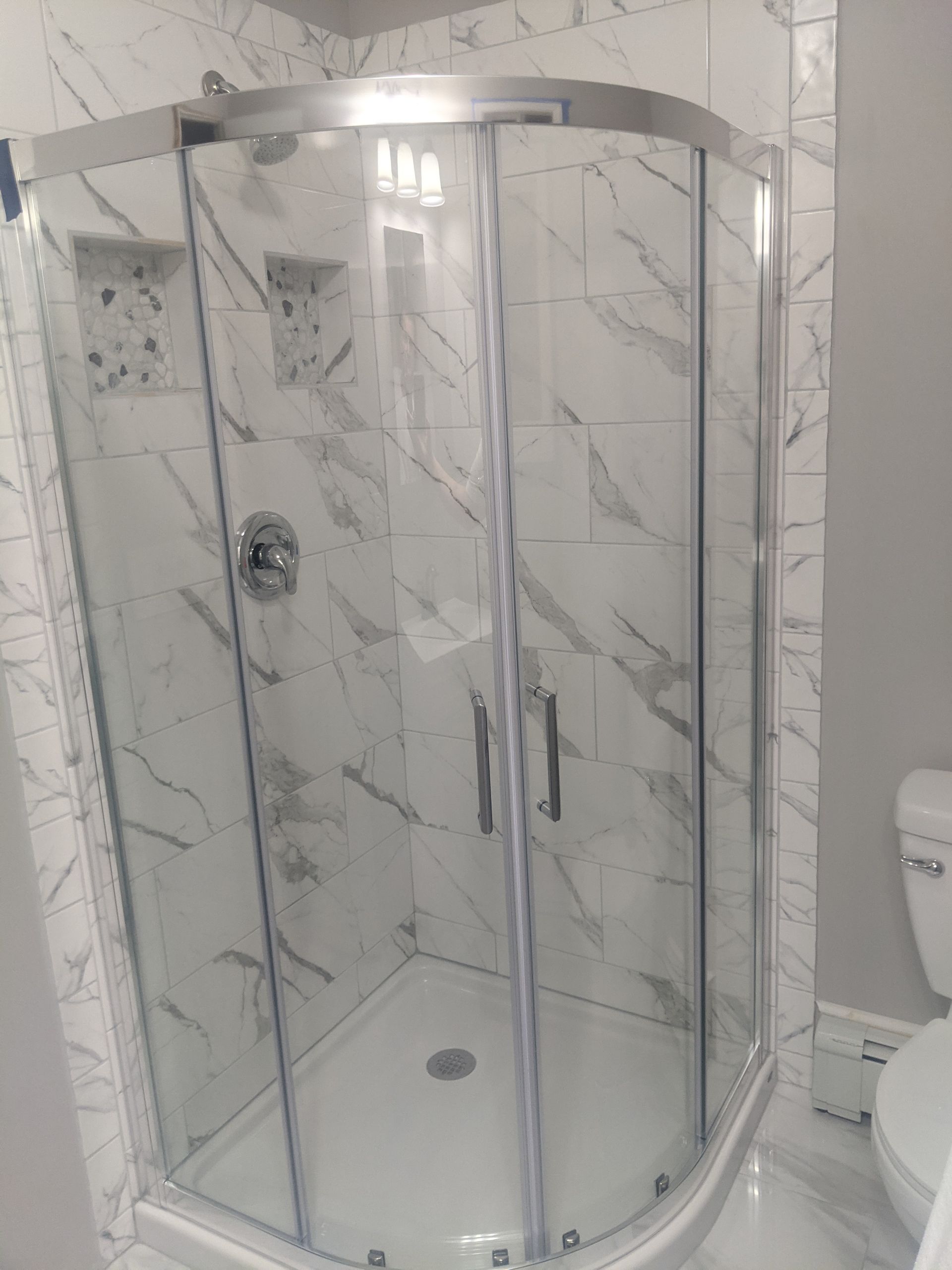A bathroom with a shower stall and a window.