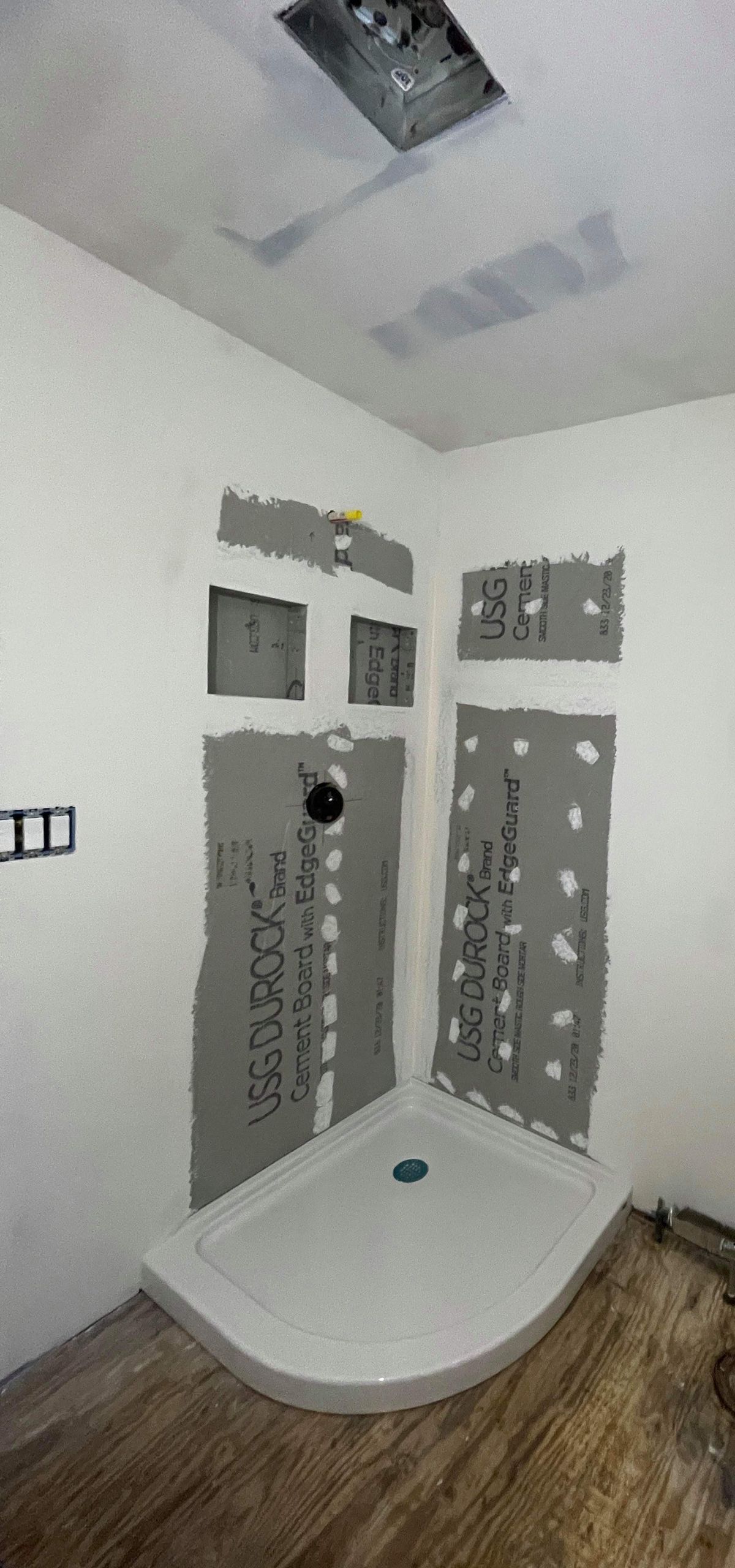 A bathroom under construction with a shower stall and a window.