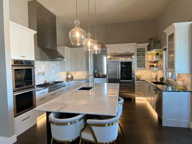 A kitchen with white cabinets and stainless steel appliances and a large island.