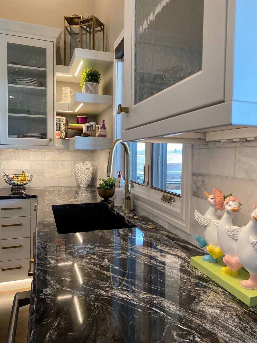 A kitchen with black granite counter tops and white cabinets