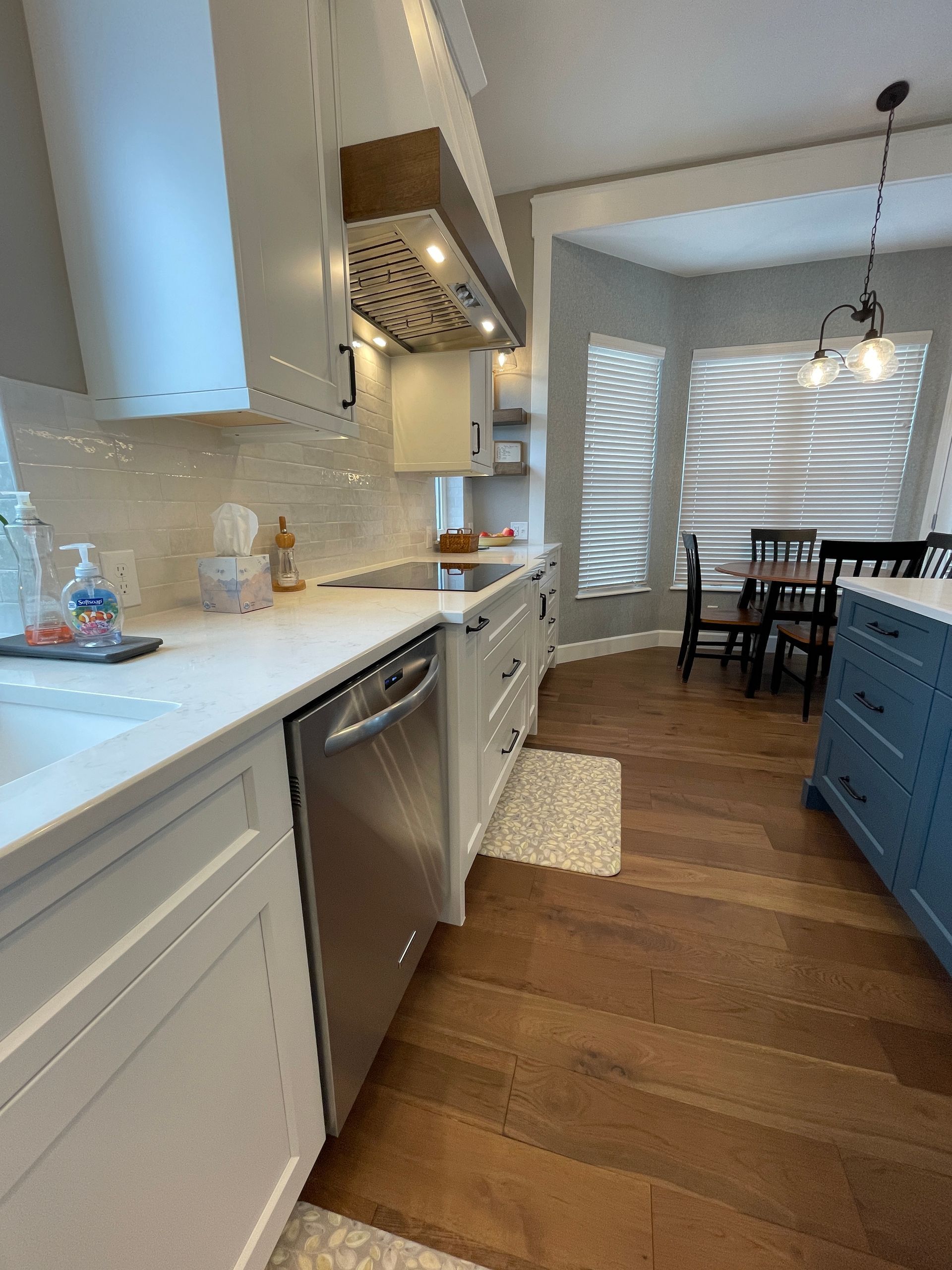A kitchen with white cabinets , stainless steel appliances , and hardwood floors.