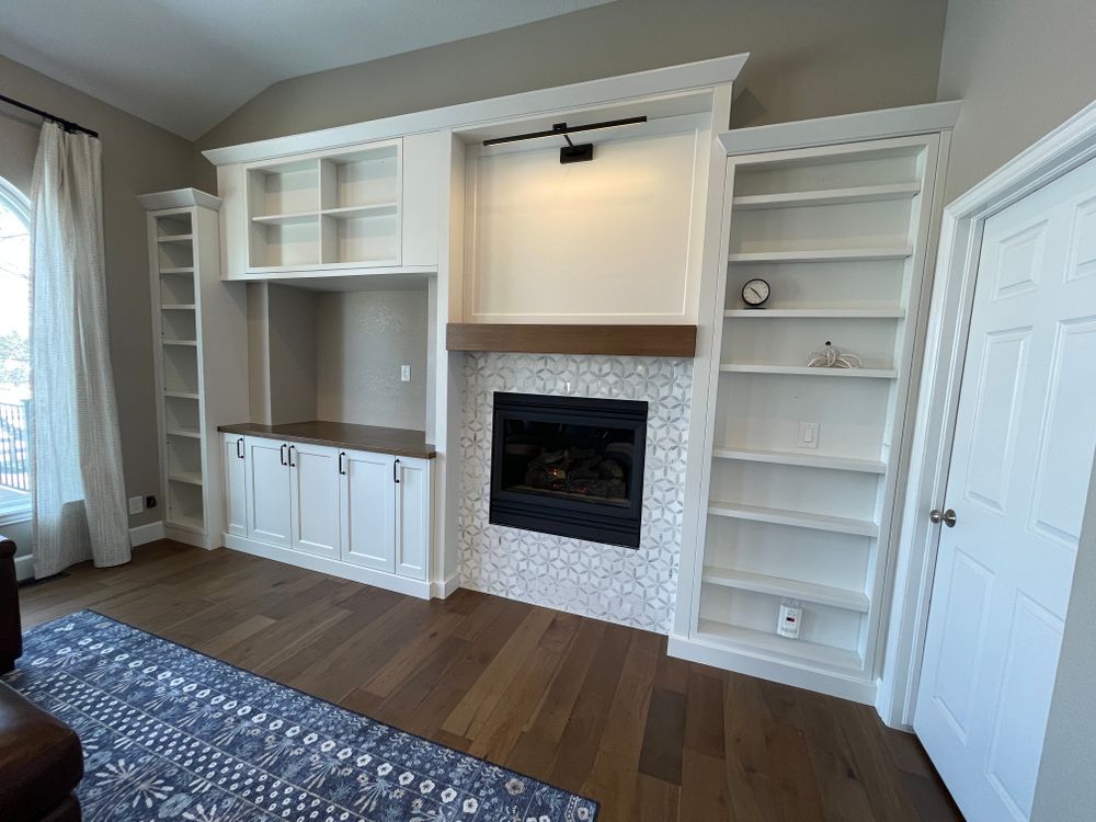 A living room with a fireplace , shelves and cabinets.