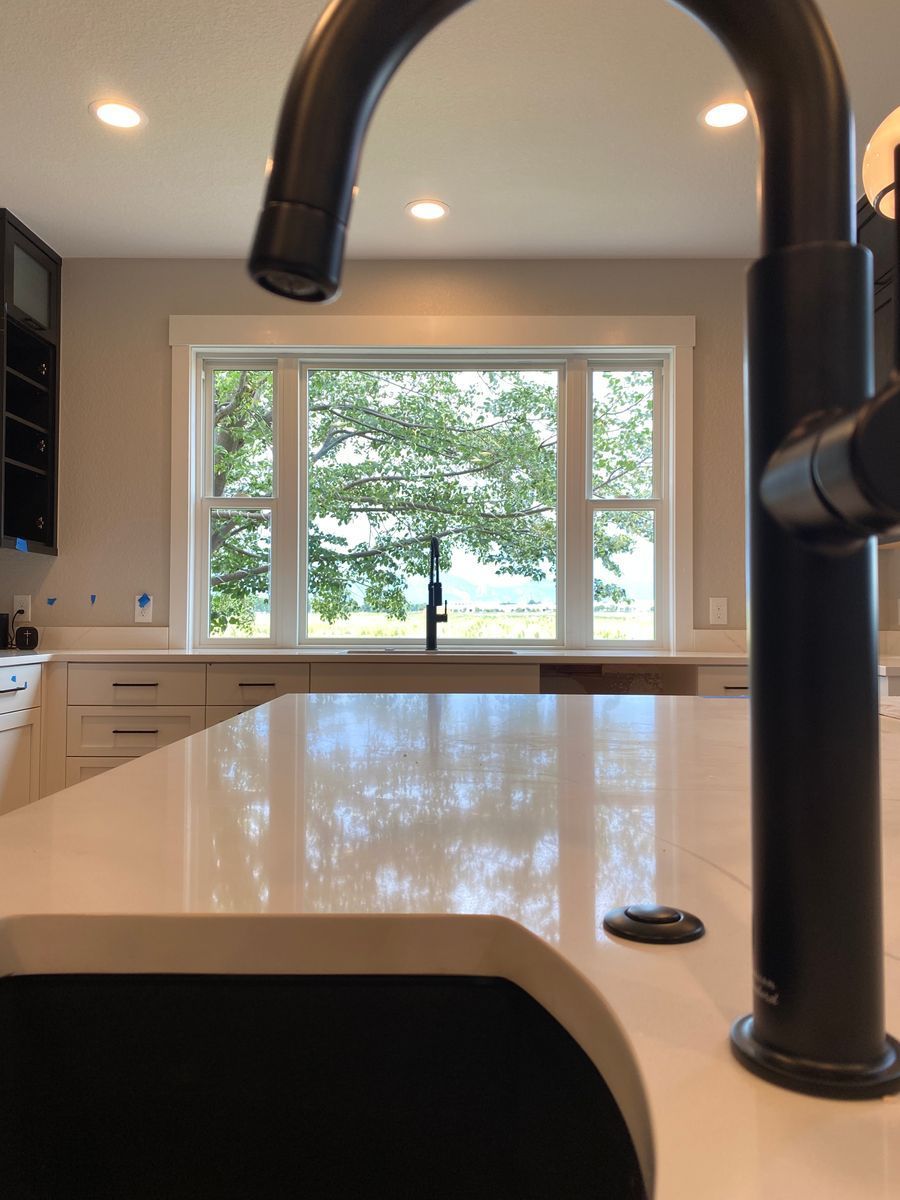A kitchen sink with a black faucet and a window in the background