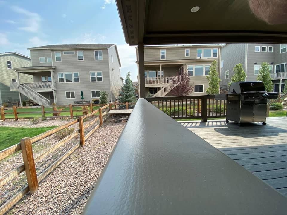 A deck with a grill and a wooden fence in the background