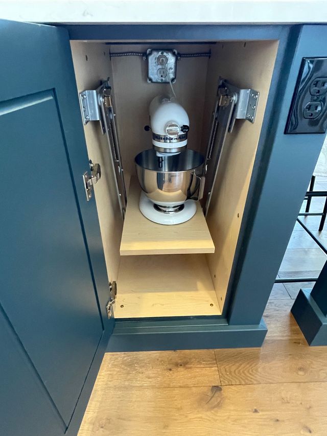 A kitchenaid mixer is sitting on a shelf in a cabinet.