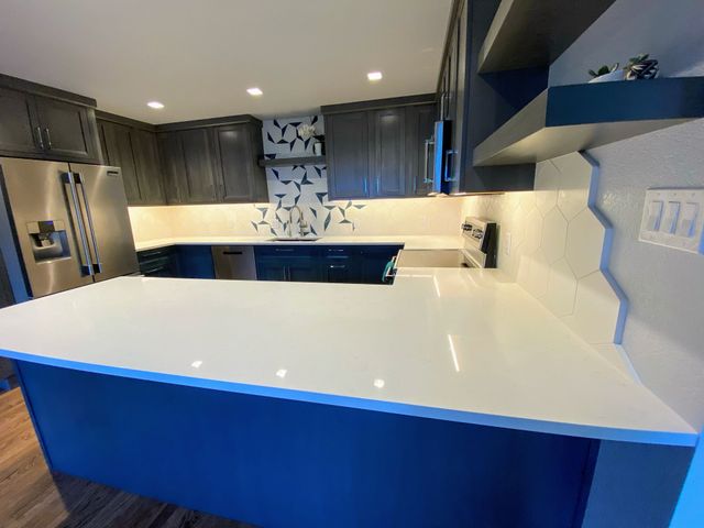 A kitchen with blue cabinets and white counter tops.