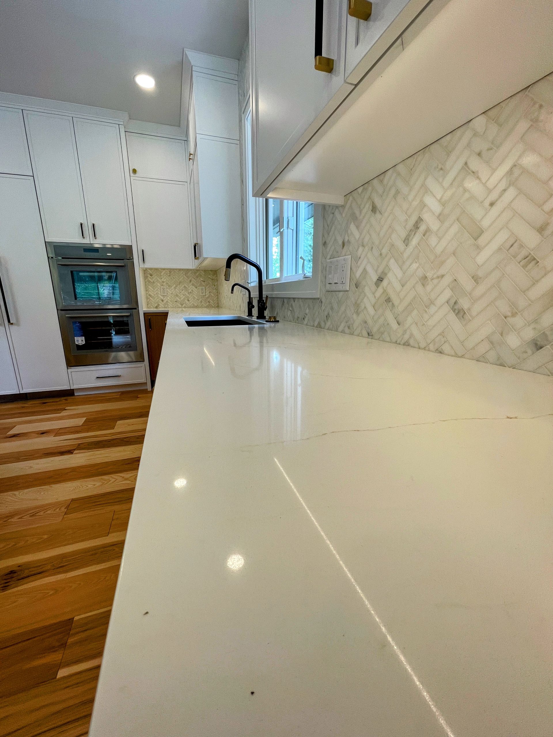 A kitchen with white counter tops and wooden floors