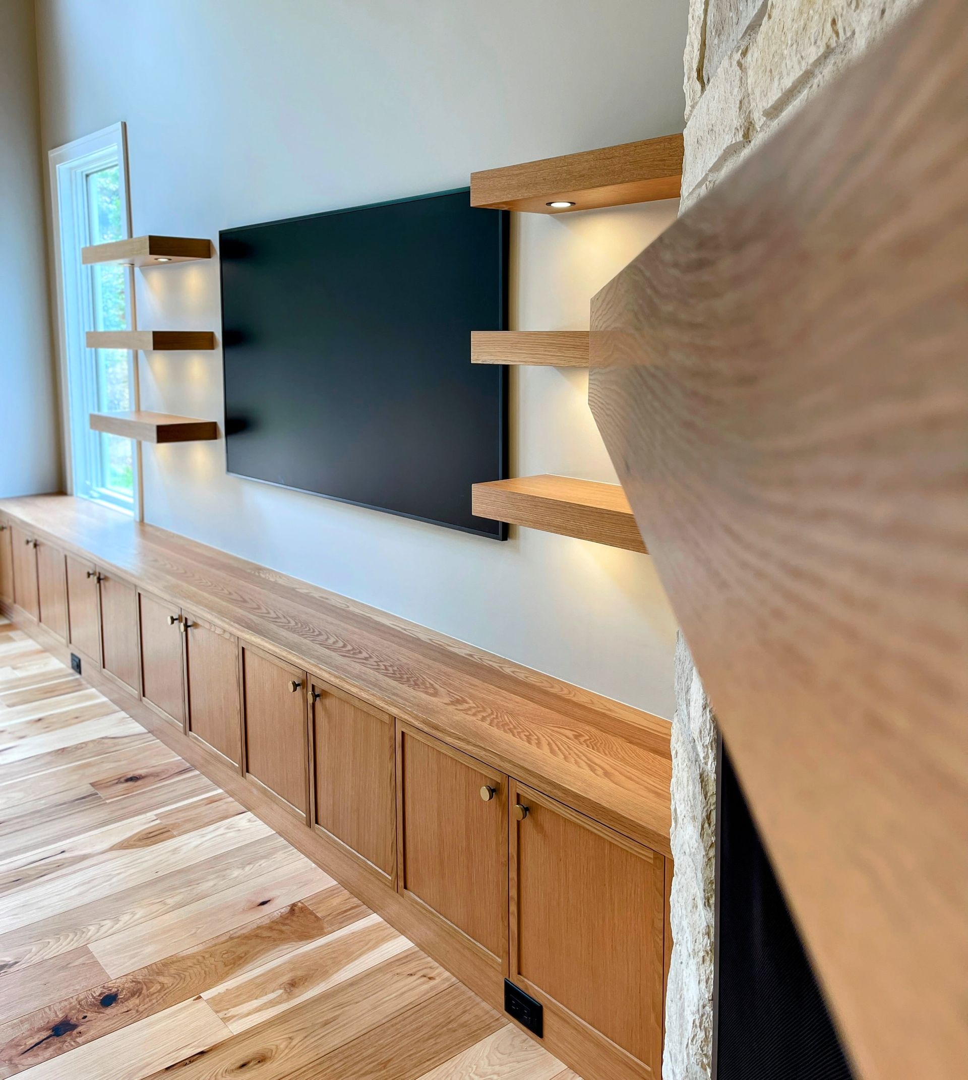 A living room with wooden cabinets and a flat screen tv on the wall