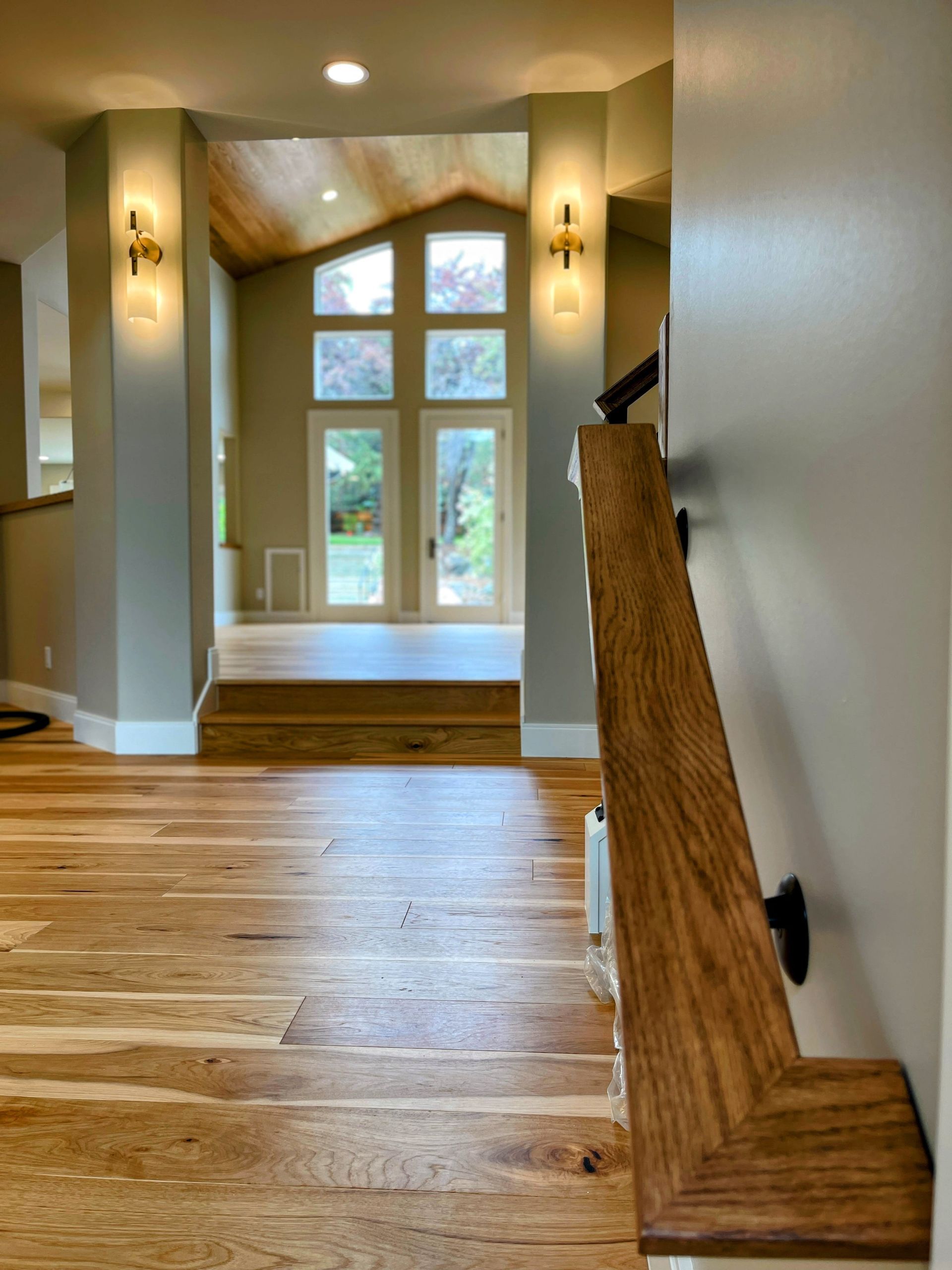 A hallway with hardwood floors and a wooden railing