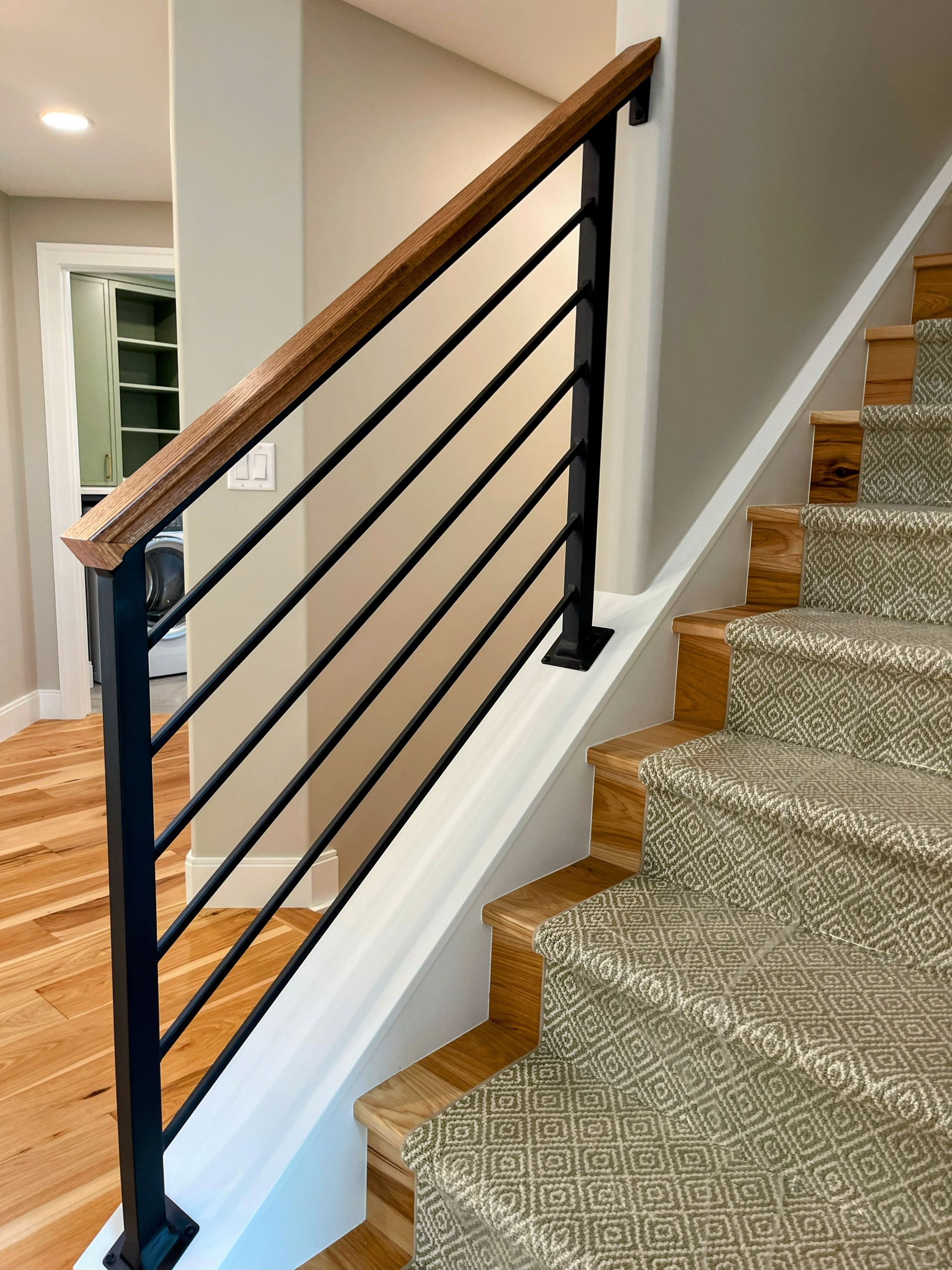 A staircase with a black railing and a wooden handrail