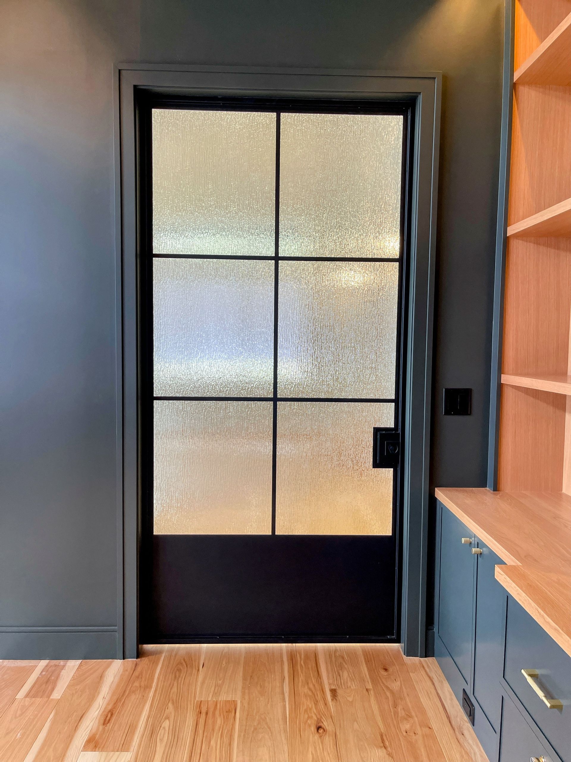 A room with a black door and a wooden floor.