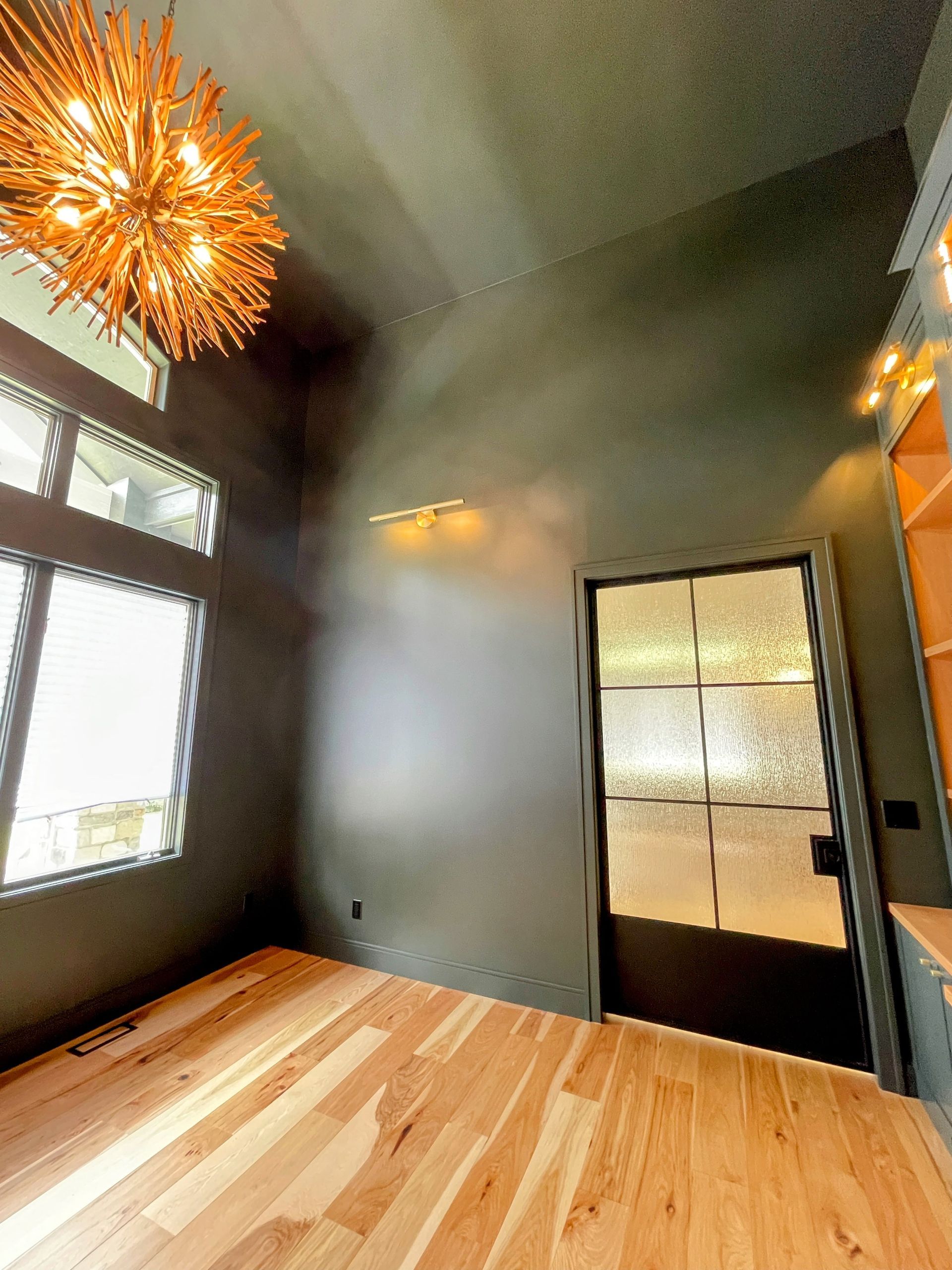 A room with a wooden floor and a chandelier hanging from the ceiling